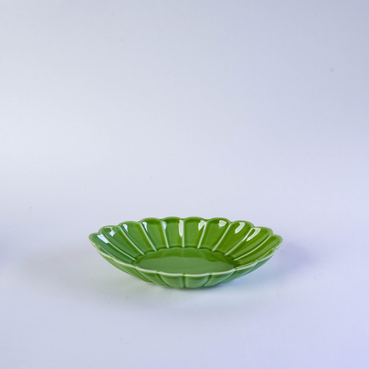 Green ceramic leaf-shaped bowl with carved details, perfect for serving salads or snacks, on a white background