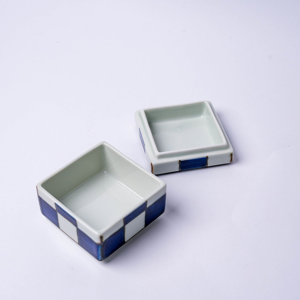 Close-up of the porcelain checkerboard trinket box with blue and white squares, showing detailed design and gold trim