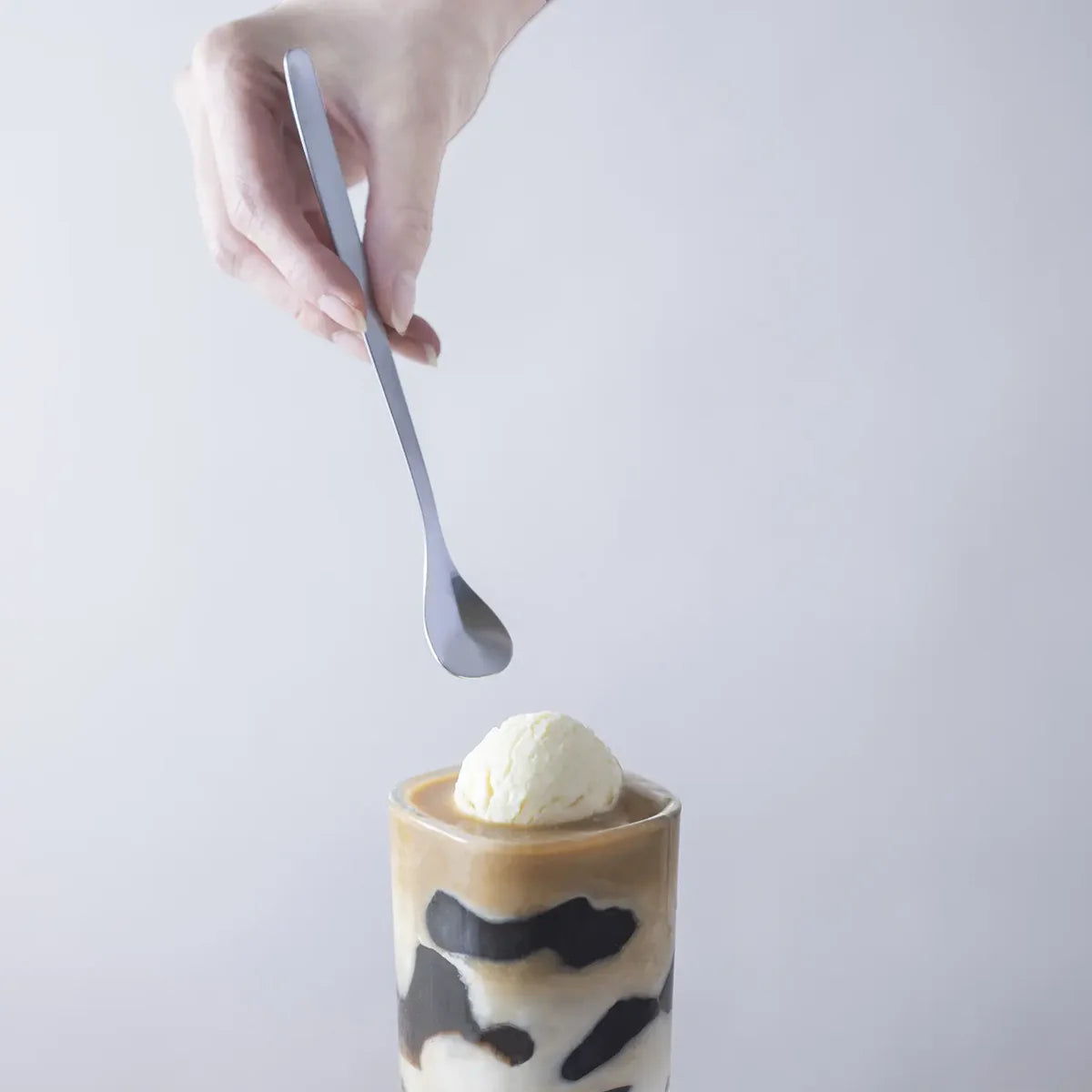 Sori Yanagi Stainless Steel Parfait Spoon in use, scooping ice cream from a dessert glass, ideal for layered treats and tall glasses.