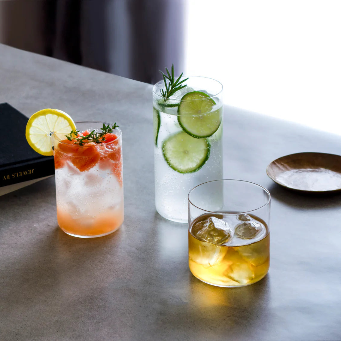 Toyo-Sasaki HS Usurai Tumblers filled with cocktails and garnishes, demonstrating their versatility and stylish appeal for home entertaining.
