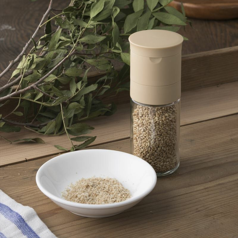 Kai Home Ceramic Sesame Grinder on wooden counter with ground sesame in dish, showcasing compact design and kitchen utility.