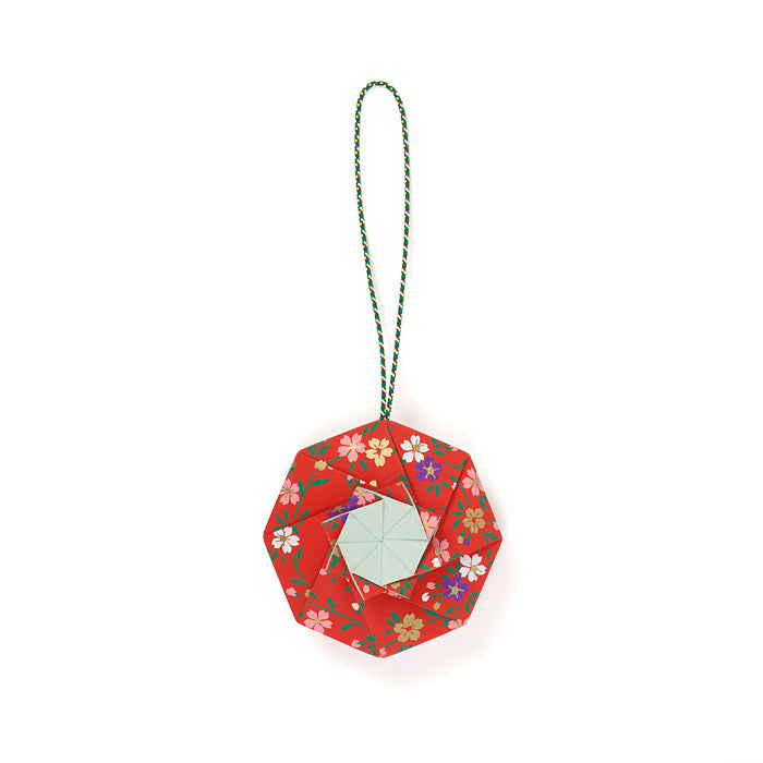 Red Shoyeido Sachet Flower Wheel with green hanging cord and pastel center, handcrafted origami with clove and spice aroma.