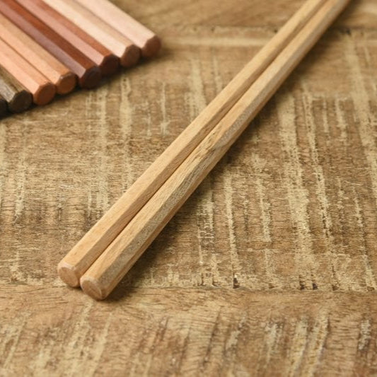 Close-up of Kawai Tetoca Chestnut Chopsticks on wooden surface, highlighting natural wood grain and square-tipped octagonal design.