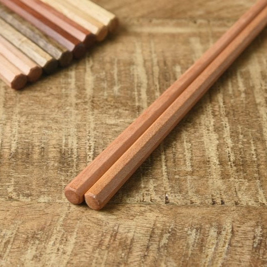 Close-up of Kawai Tetoca Chopsticks - Mandarine Wood on wooden surface, highlighting anti-roll shape and smooth beeswax-coated texture.