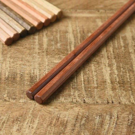 Close-up of Kawai Tetoca Chopsticks - Peach Wood on wooden surface, highlighting octagonal shape and smooth beeswax-coated texture.
