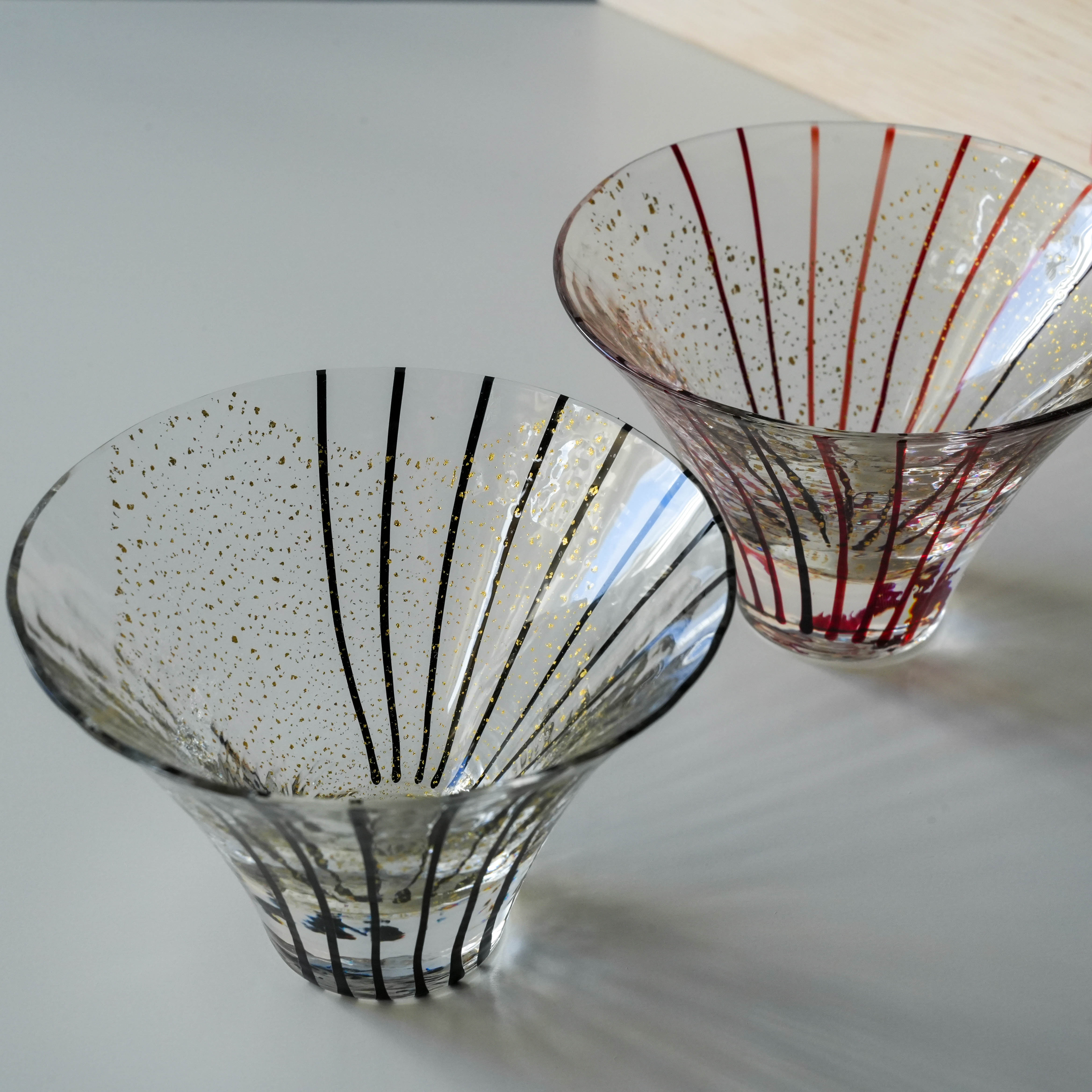 Close-up of Toyo-Sasaki Edo Glass Sake Cups showcasing gold detailing and striped patterns. Handcrafted Japanese drinkware set.