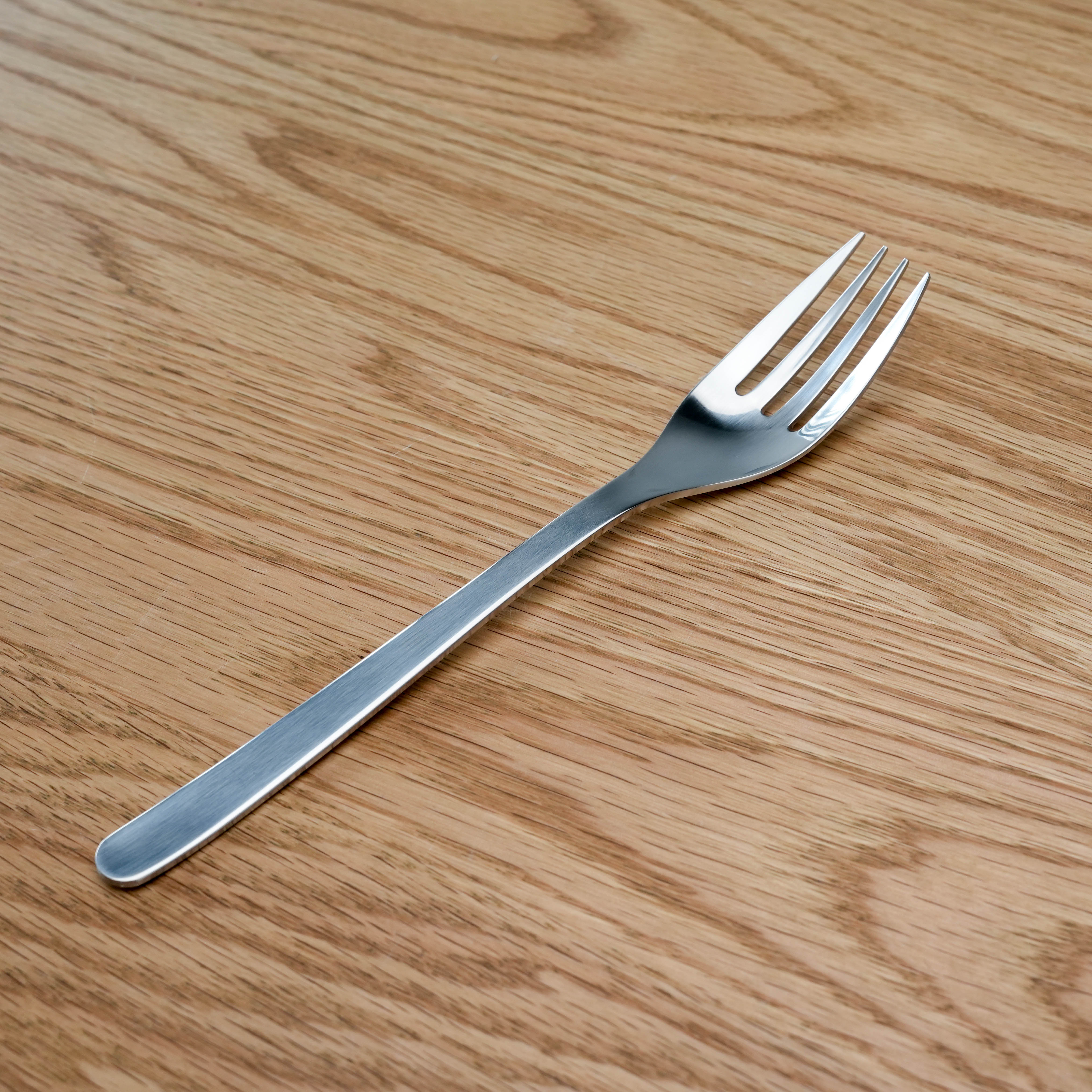 Sori Yanagi Pasta Fork - Stainless Steel | Japanese Design utensil with sleek, ergonomic handle on wood surface. Ideal for serving pasta dishes.