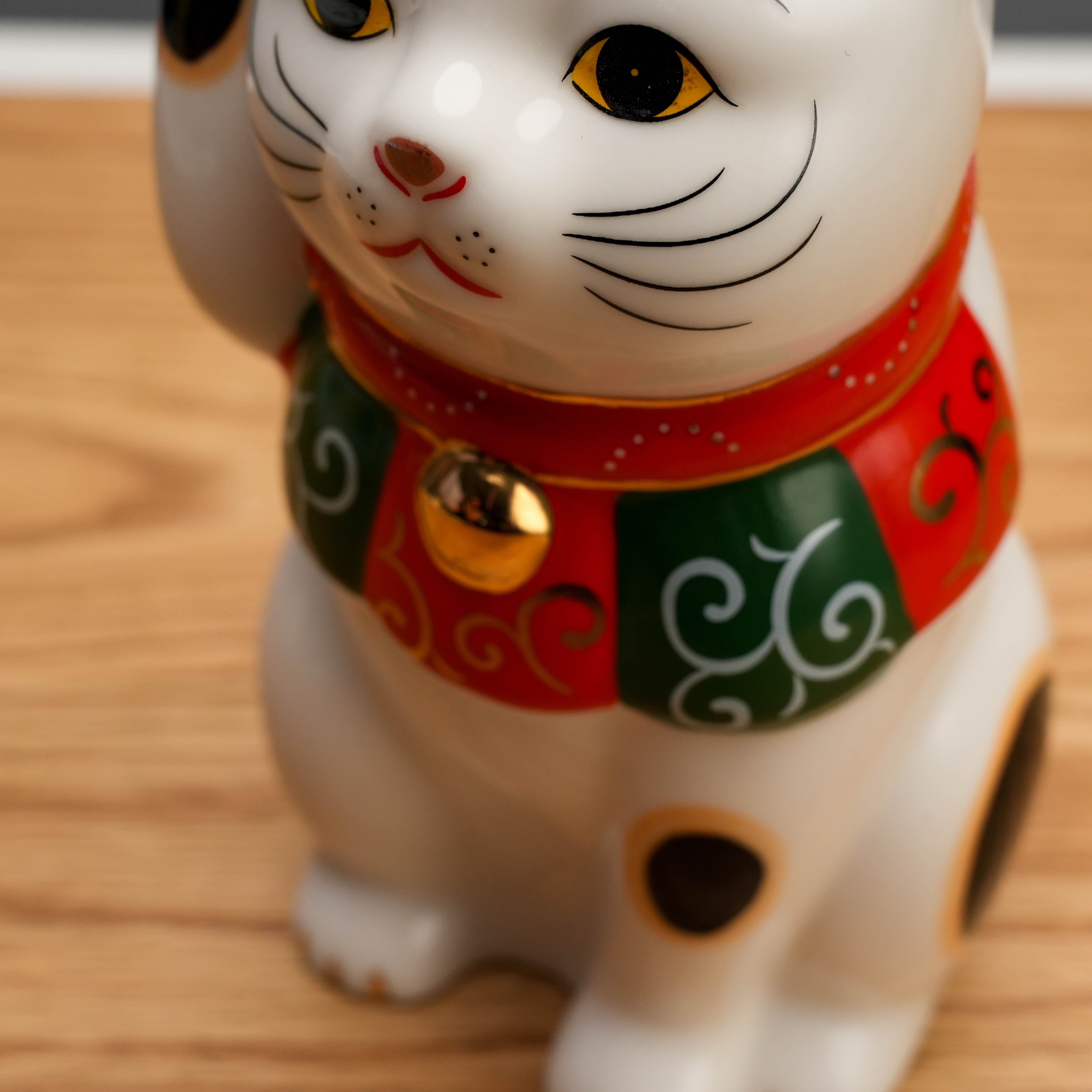 Close-up of Yakushigama Arabesque Scarf Beckoning Cat showing detailed arabesque scarf and golden bell, handcrafted for decorative charm.