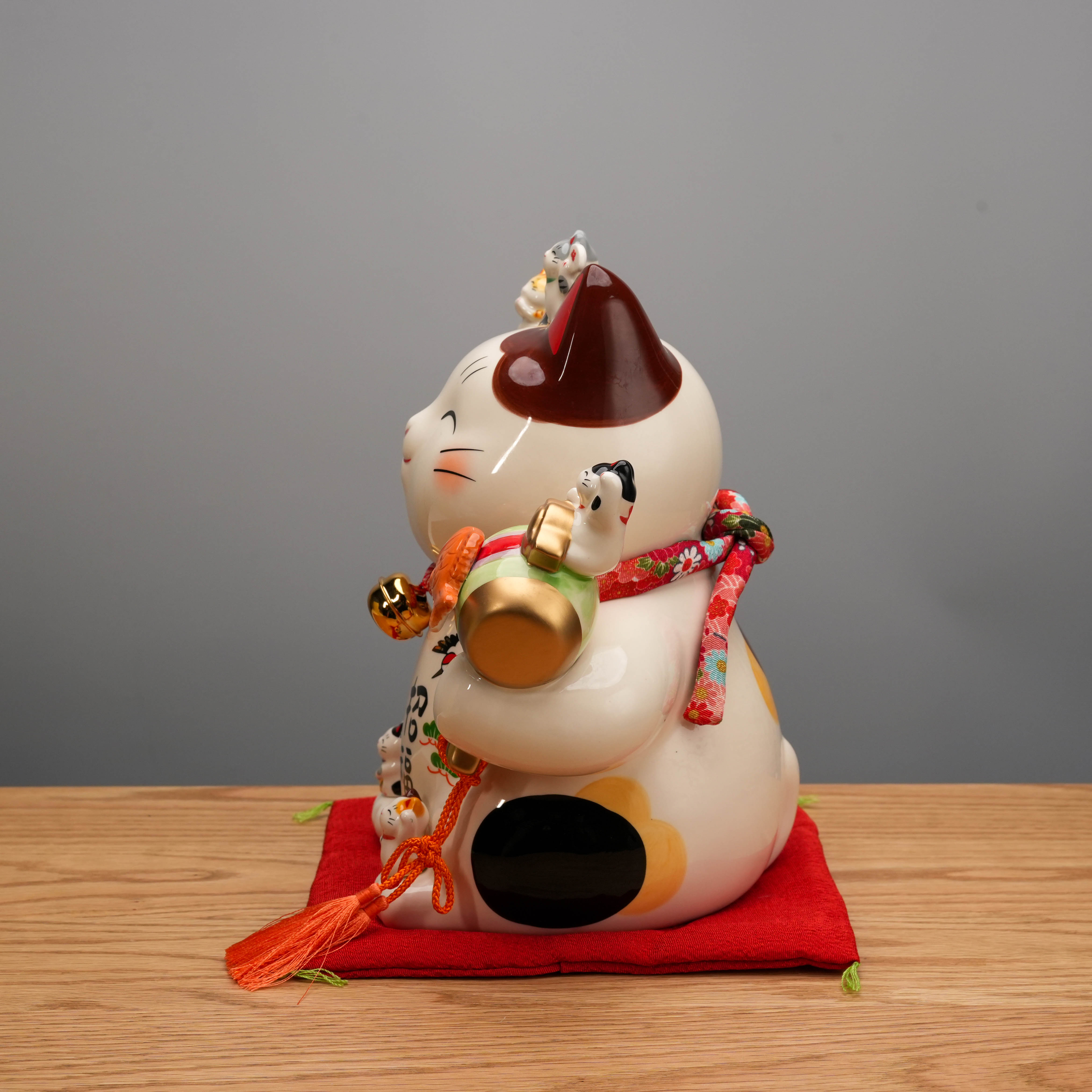 Side view of Yakushigama Bliss Beckoning Cat showing detailed ceramic craftsmanship and vibrant accessories, ideal for home decor and good fortune.