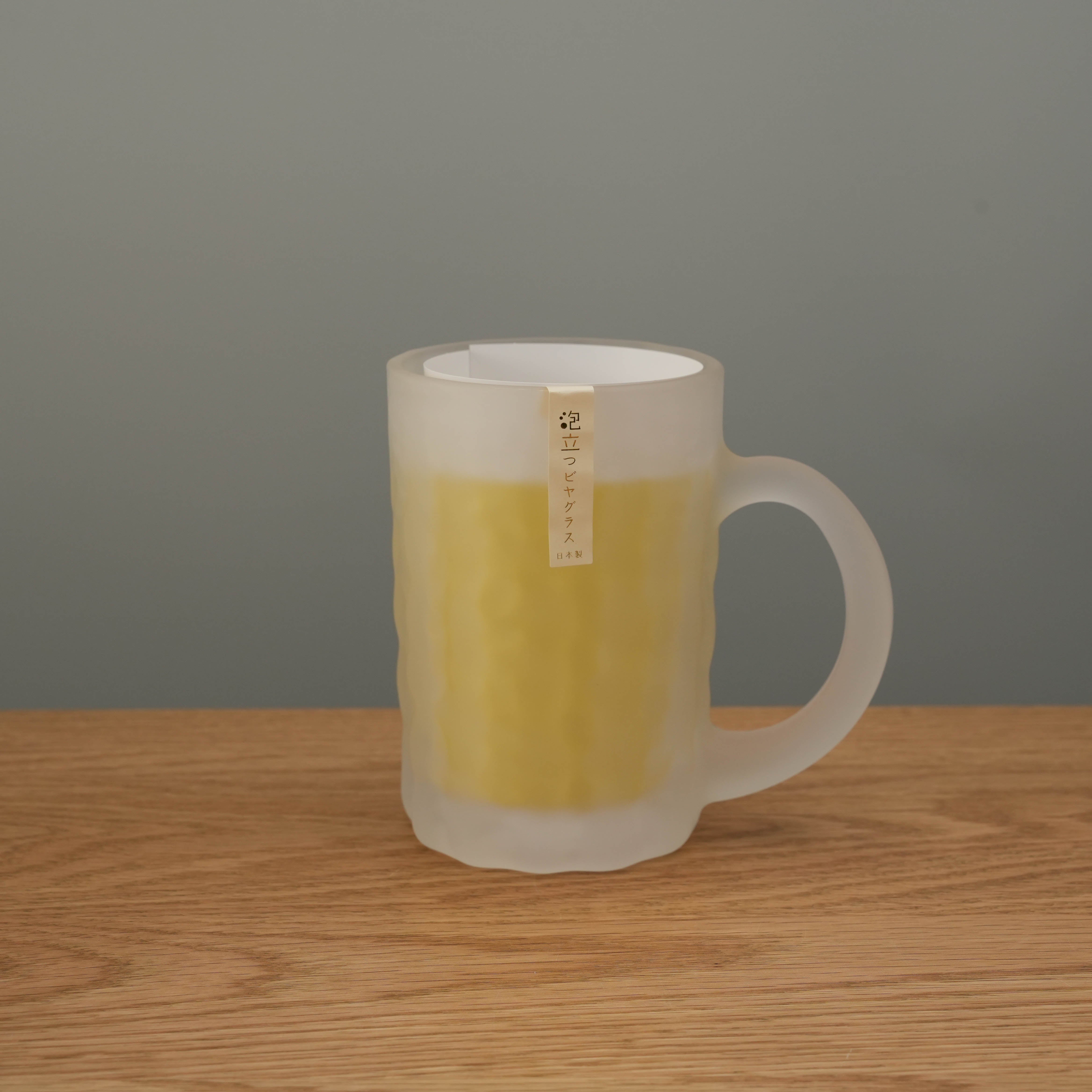 Toyo-Sasaki Frosted Glass Beer Mug filled with beer on wooden surface. Made in Japan, ideal for enhancing creamy beer bubbles.