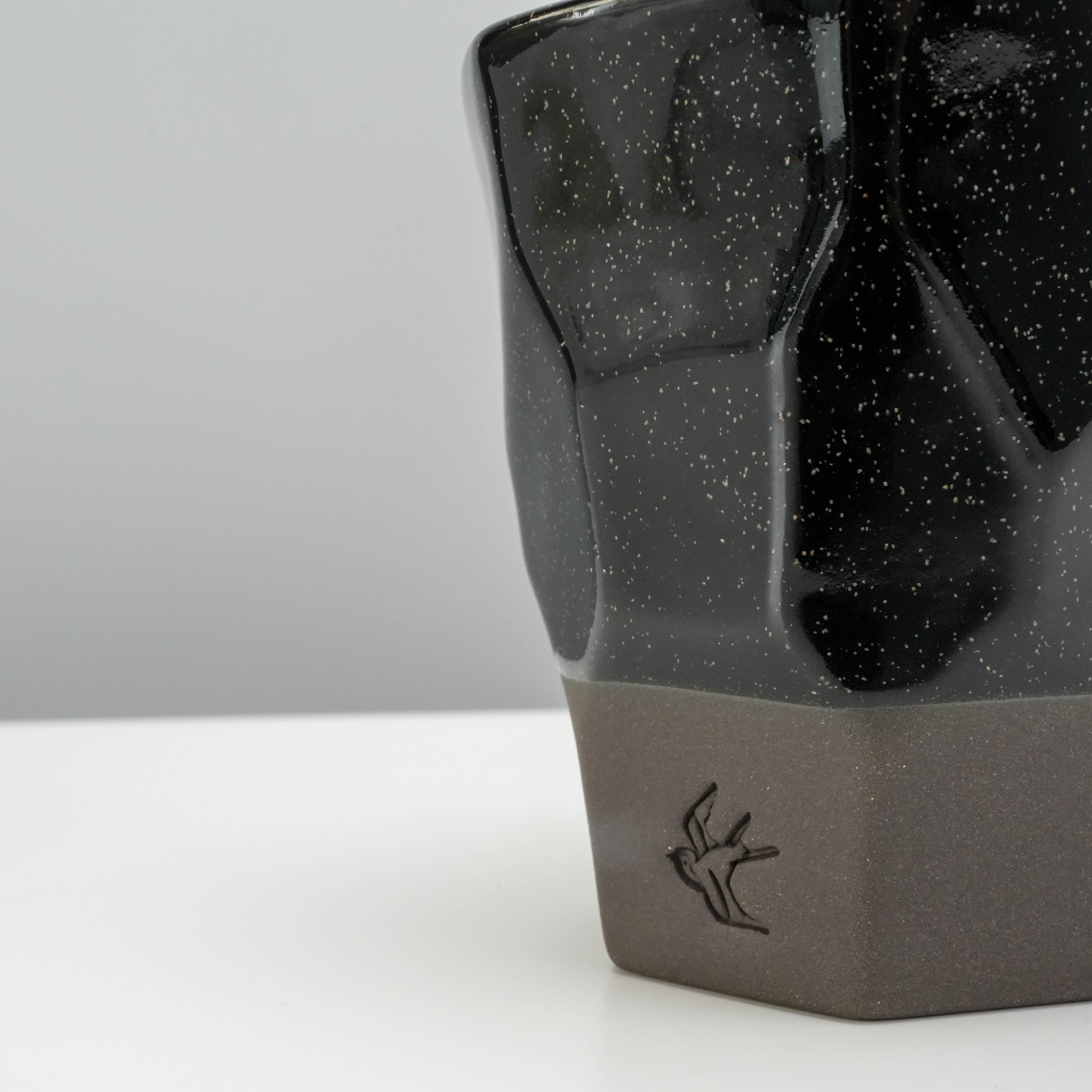 Close-up of Tsubame Kobo Free Cup base with embossed bird logo and matte black clay texture, showcasing artisanal craftsmanship.