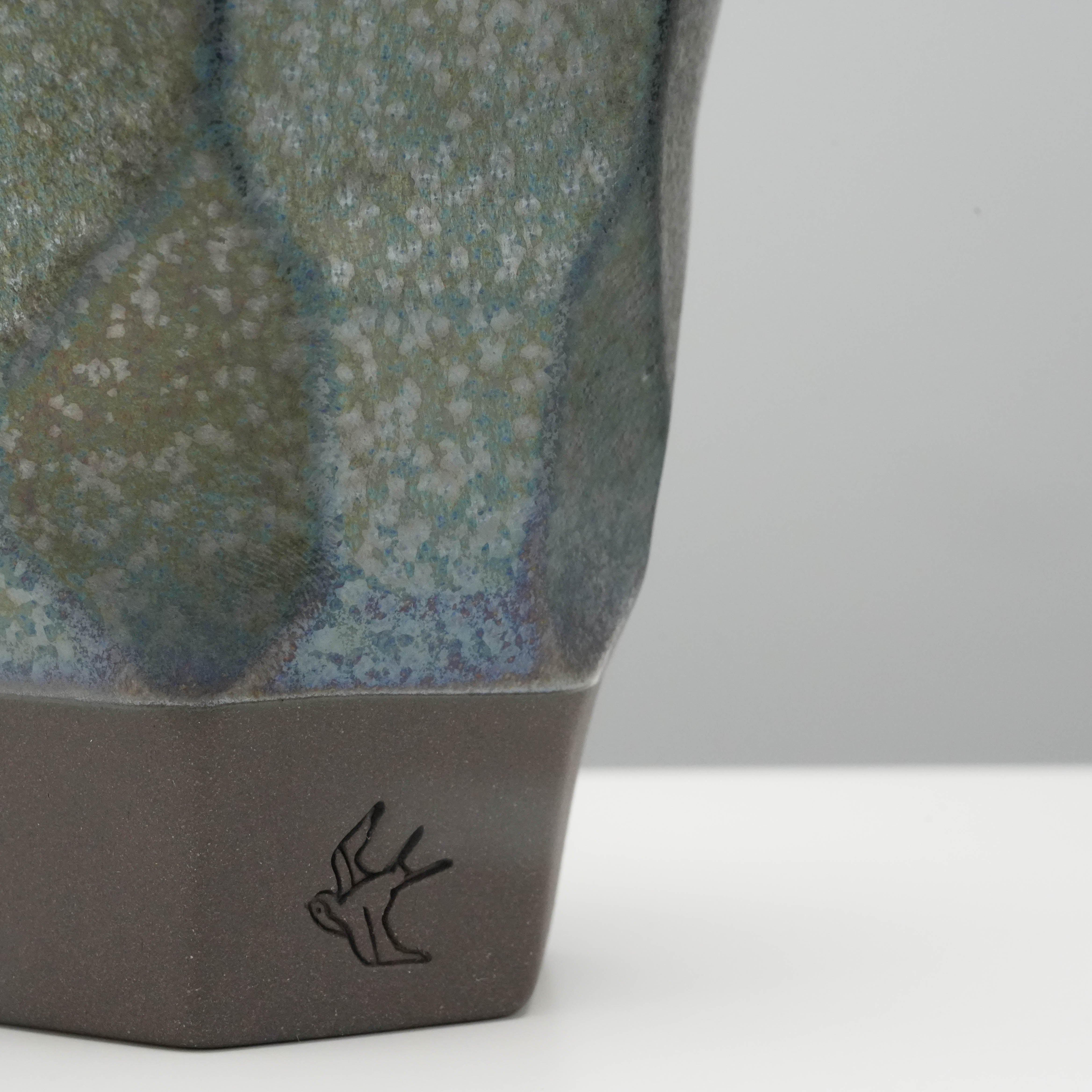 Close-up of Tsubame Kobo Free Cup - Metal Cup base showing black clay texture and engraved swallow logo, highlighting artisanal detail.