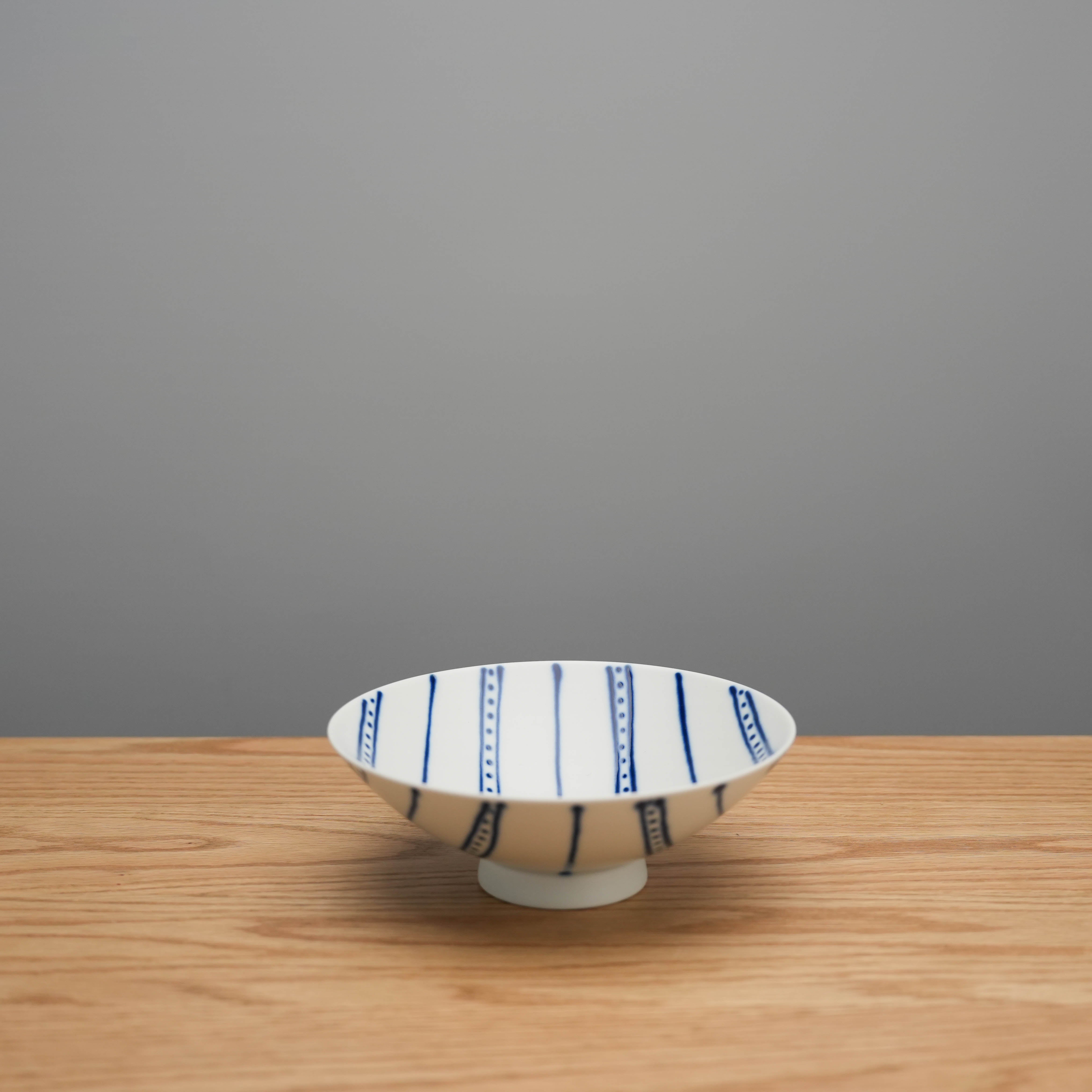 Hasami Ware Flat Bowl Blue with vertical blue stripes on white ceramic, ideal for serving side dishes or rice in modern kitchens.