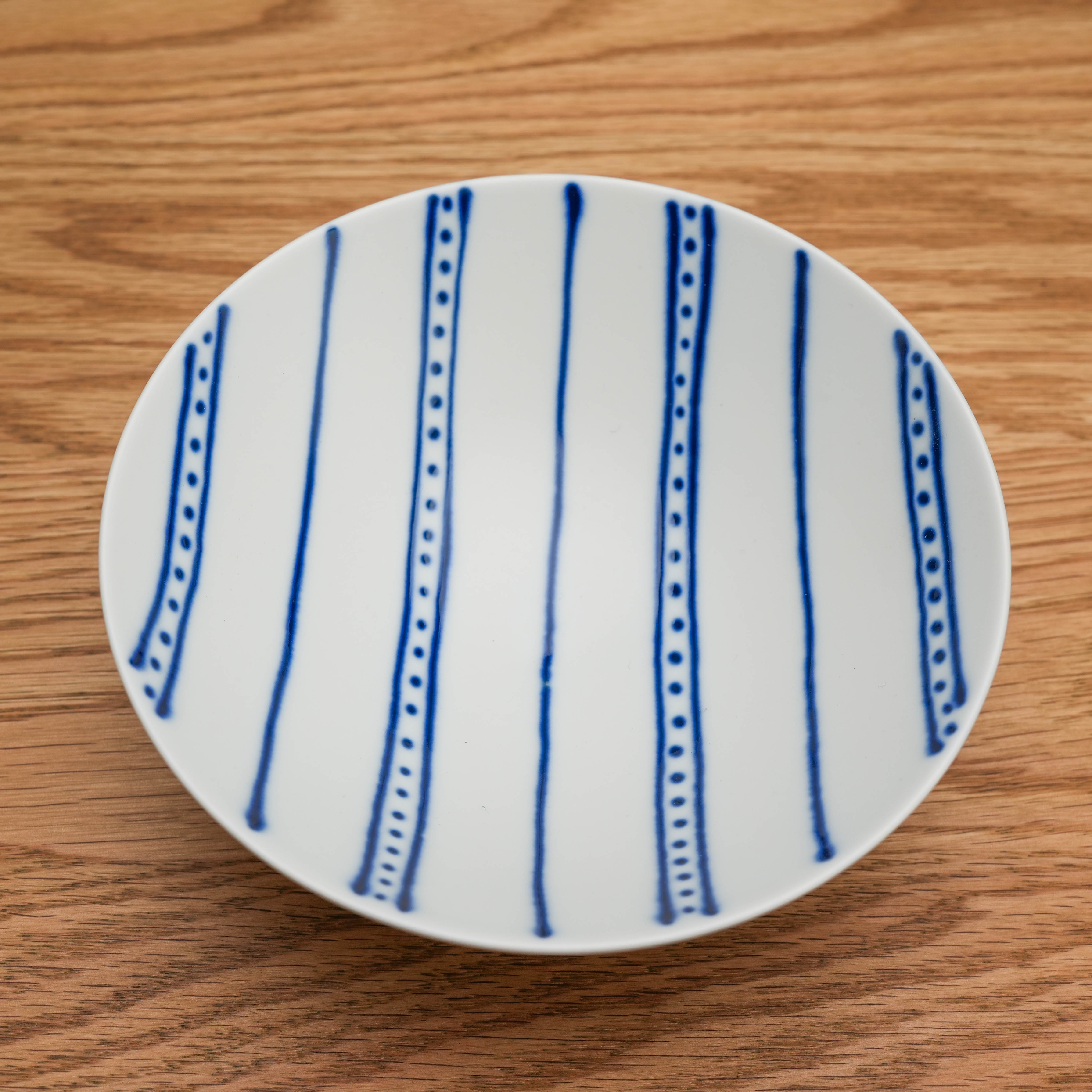 Top view of Hasami Ware Flat Bowl Blue featuring hand-painted vertical blue lines, a stylish ceramic bowl for food storage or presentation.