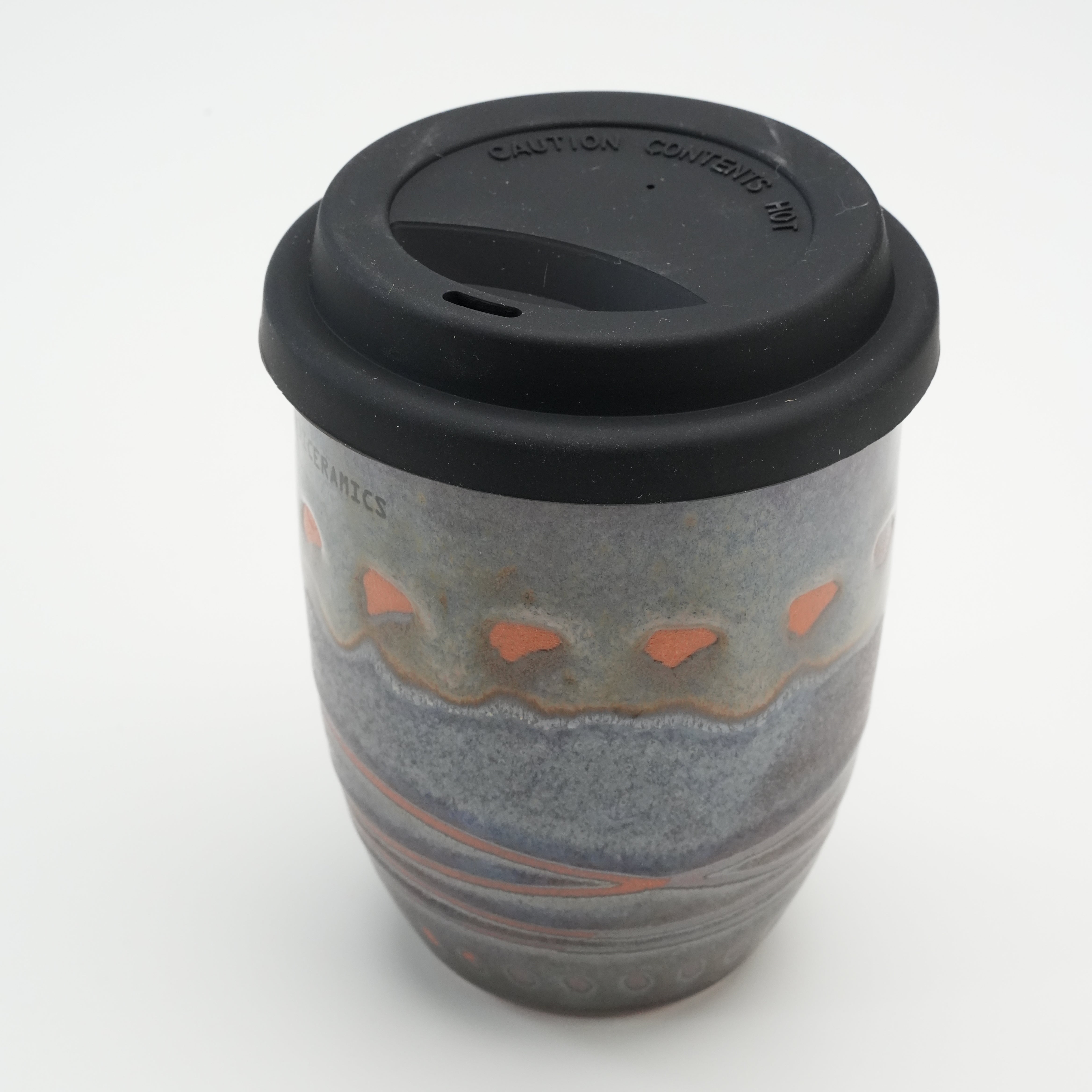 Angled view of Handiceramics Acorn Travel Cup with lid, emphasizing unique handmade ceramic pattern and ergonomic drinking spout.
