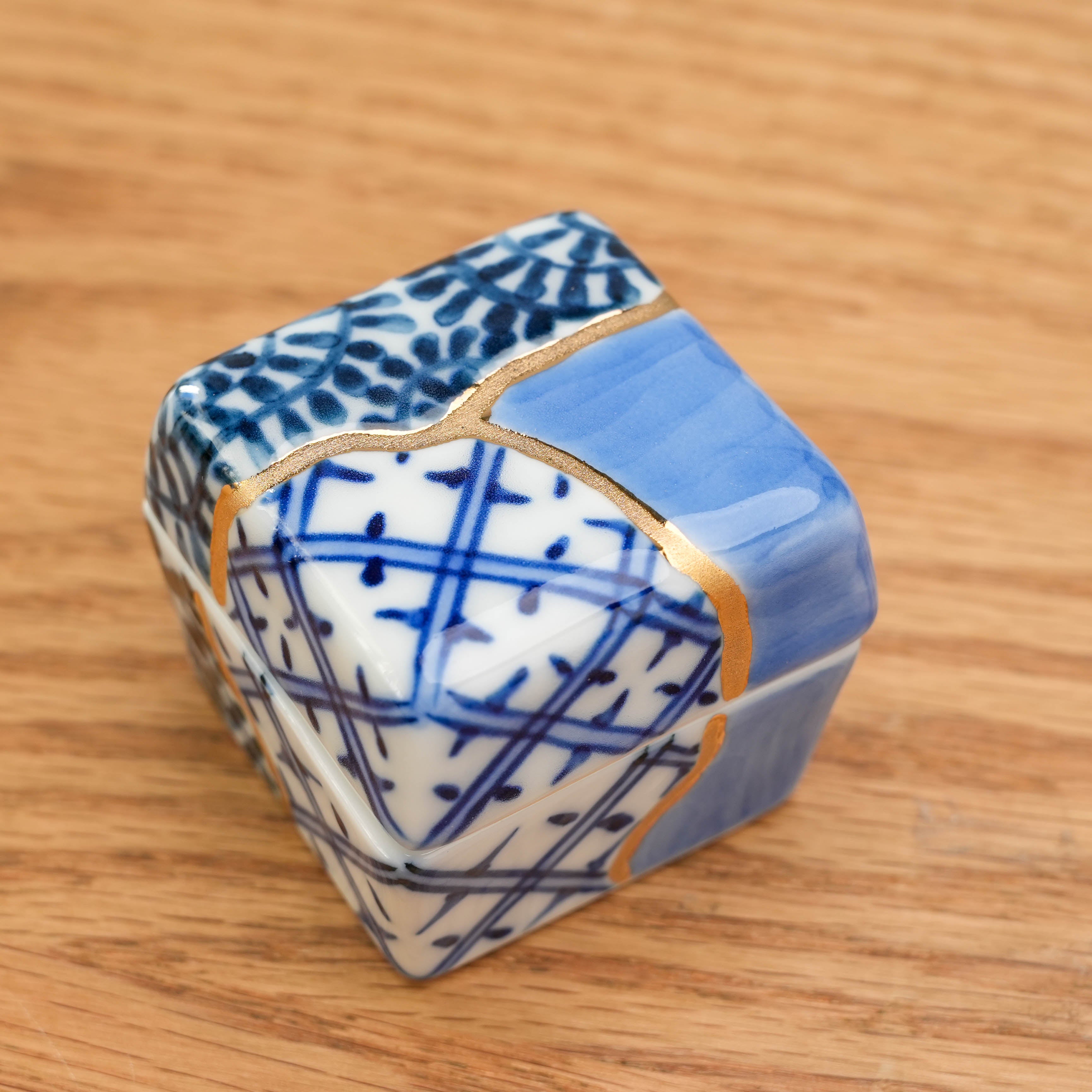 Top view of Arita kintsugi-style Delicacy Container highlighting gold kintsugi lines and intricate blue patterns. A refined touch for dining settings.