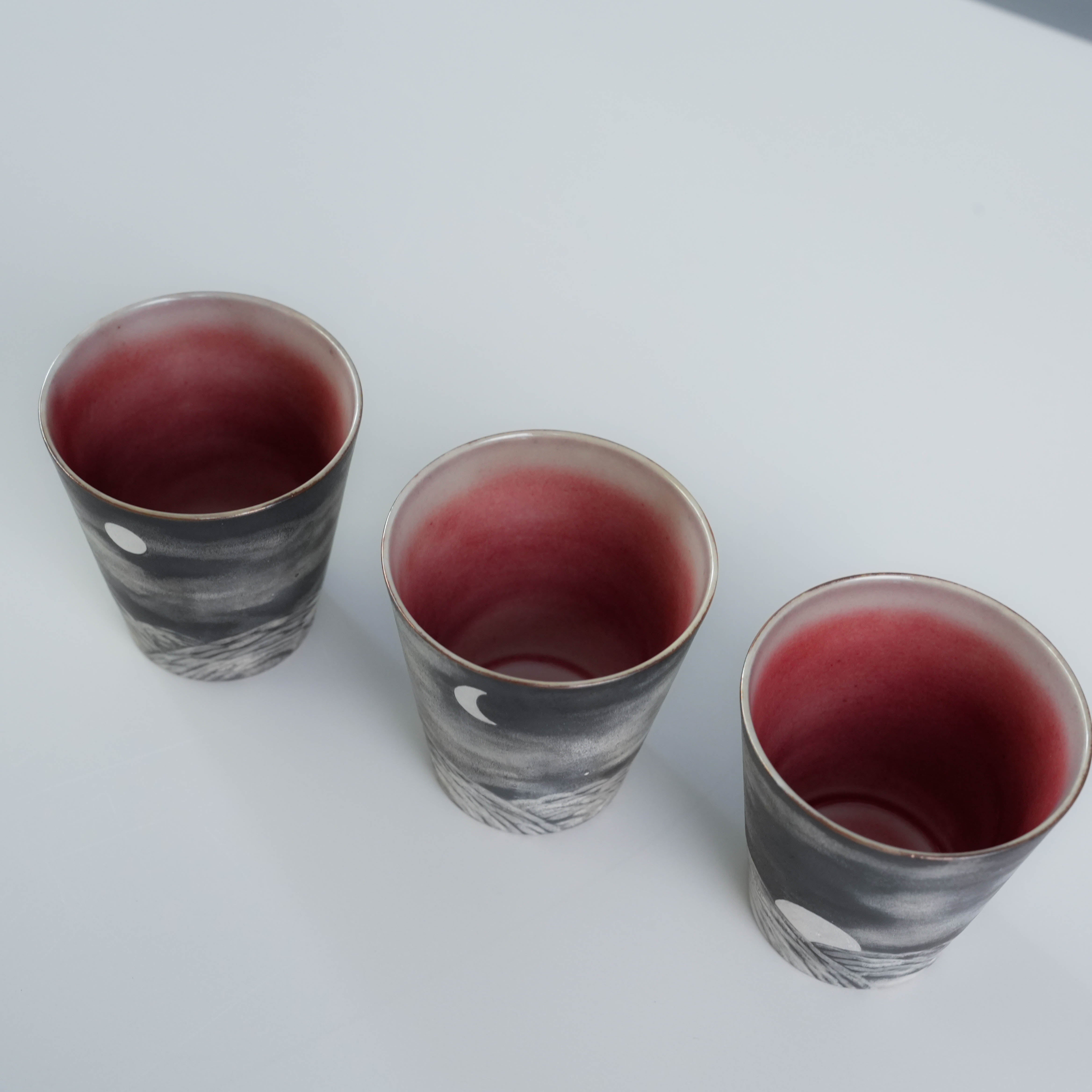 Top view of three Lonesome Studio Qushui tea cups with red interiors and silver-glazed exteriors, part of Gongfu Cha handmade tea set.