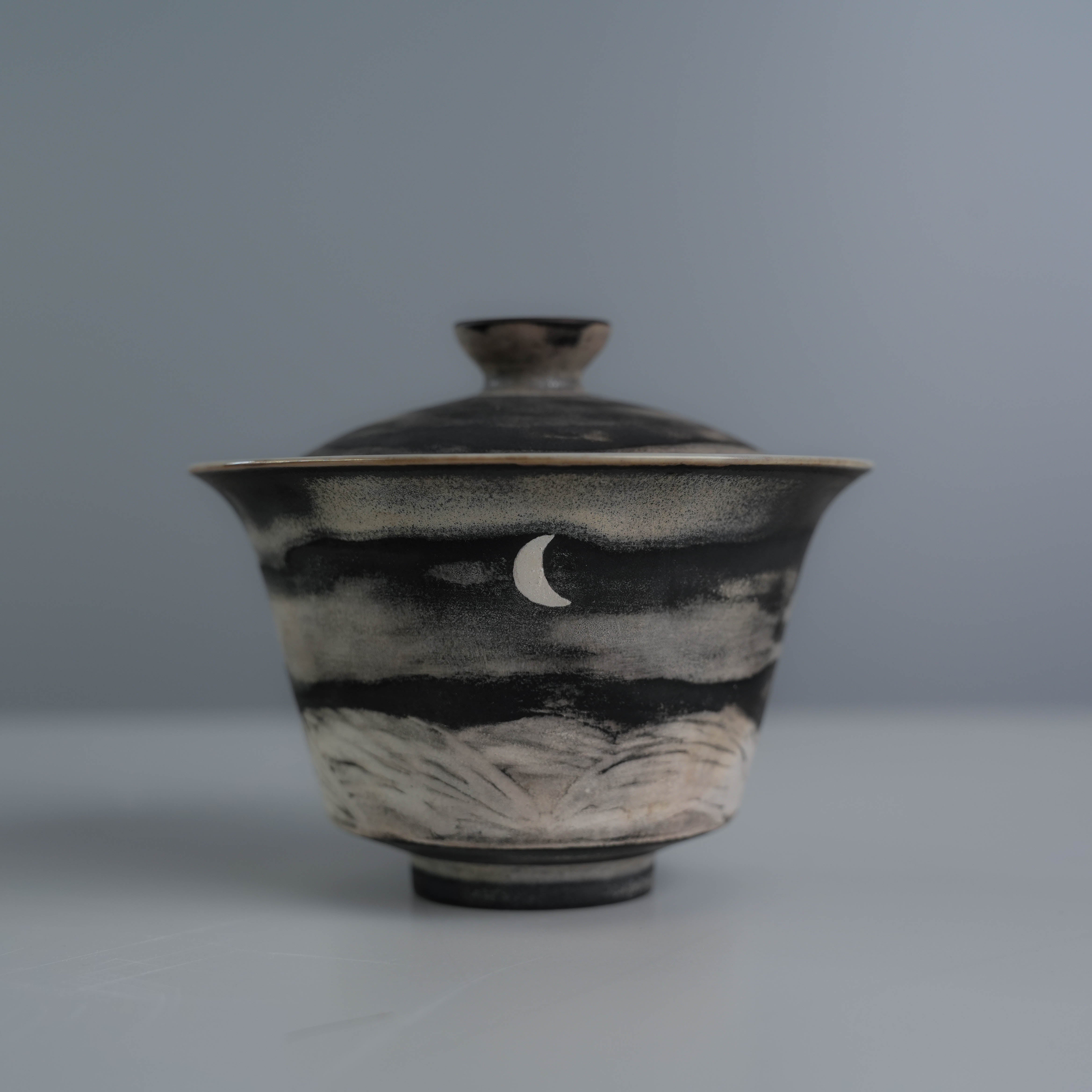 Front view of Lonesome Studio Qushui gaiwan with crescent moon and mountain design, handmade with silver glaze for Gongfu Cha tea rituals.