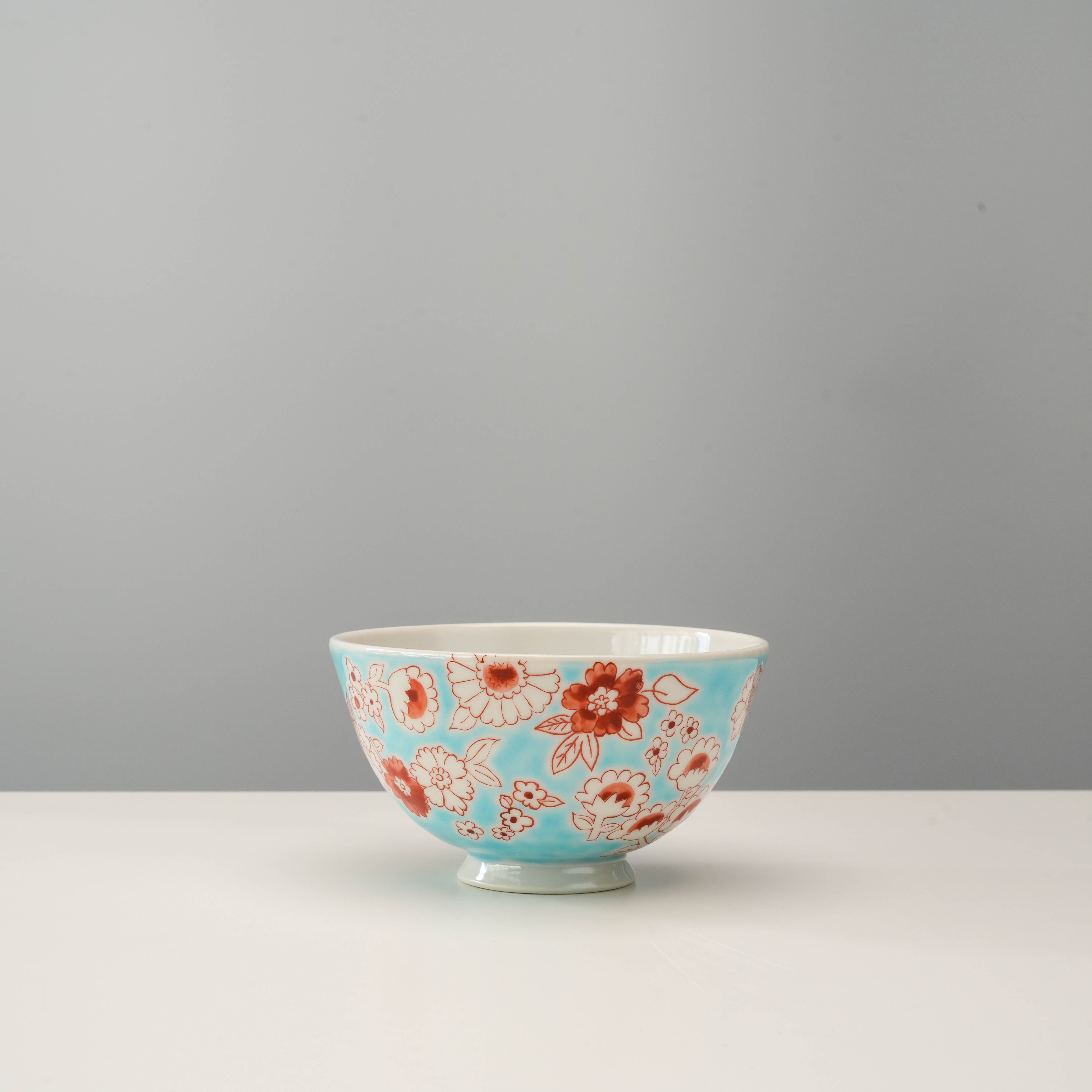 Lightweight Kutani Ware rice bowl featuring a vibrant red and white flower shower design on blue porcelain, perfect for everyday dining.