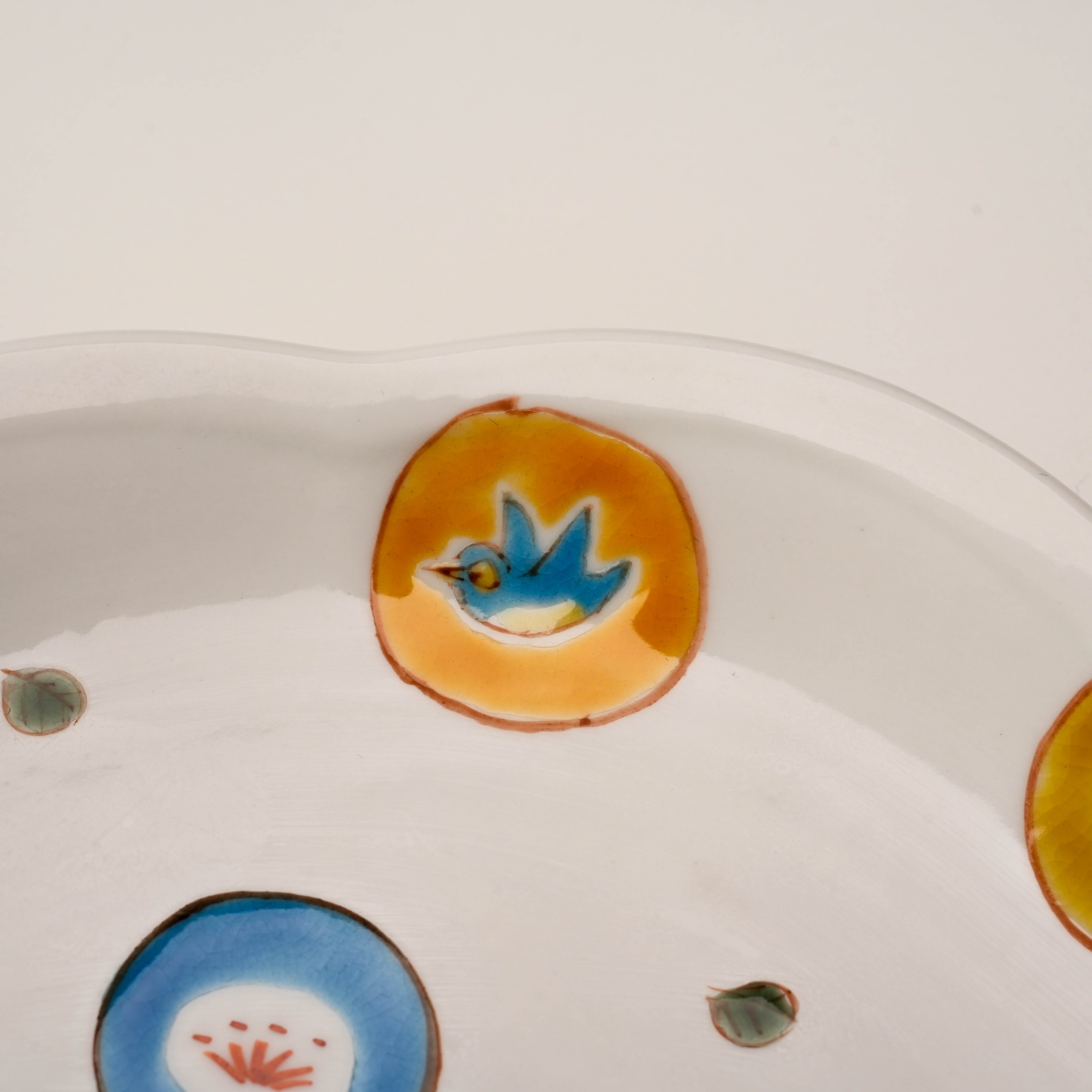Close-up of Kutani Ware Serving Plate – Marumon Mizutama showing detailed hand-painted blue bird within an orange circle. Traditional Japanese craftsmanship.
