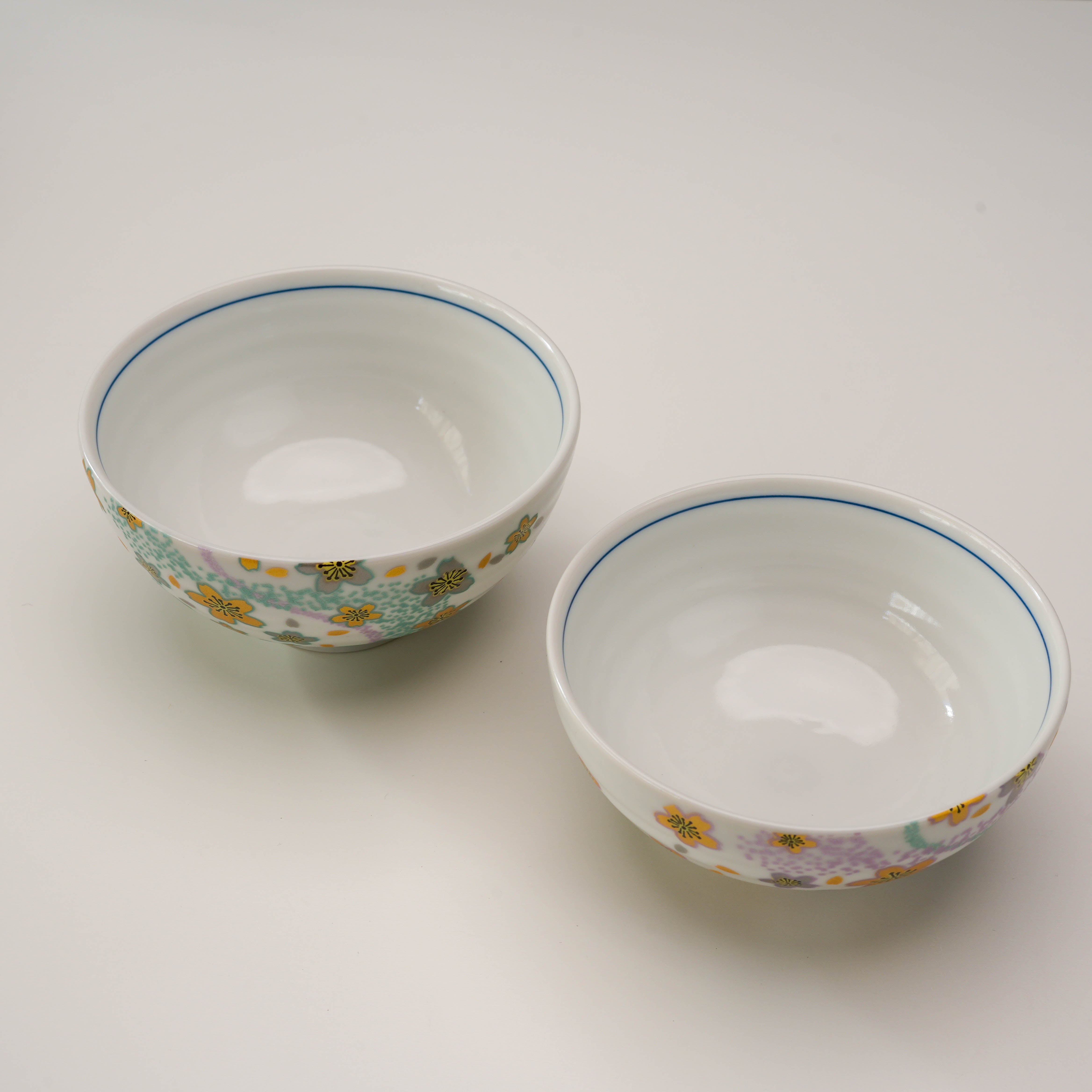 Top view of Kutani Ware Kyokusui Flower Rice Bowl Set showing smooth white interiors and delicate floral exteriors, perfect for couples.