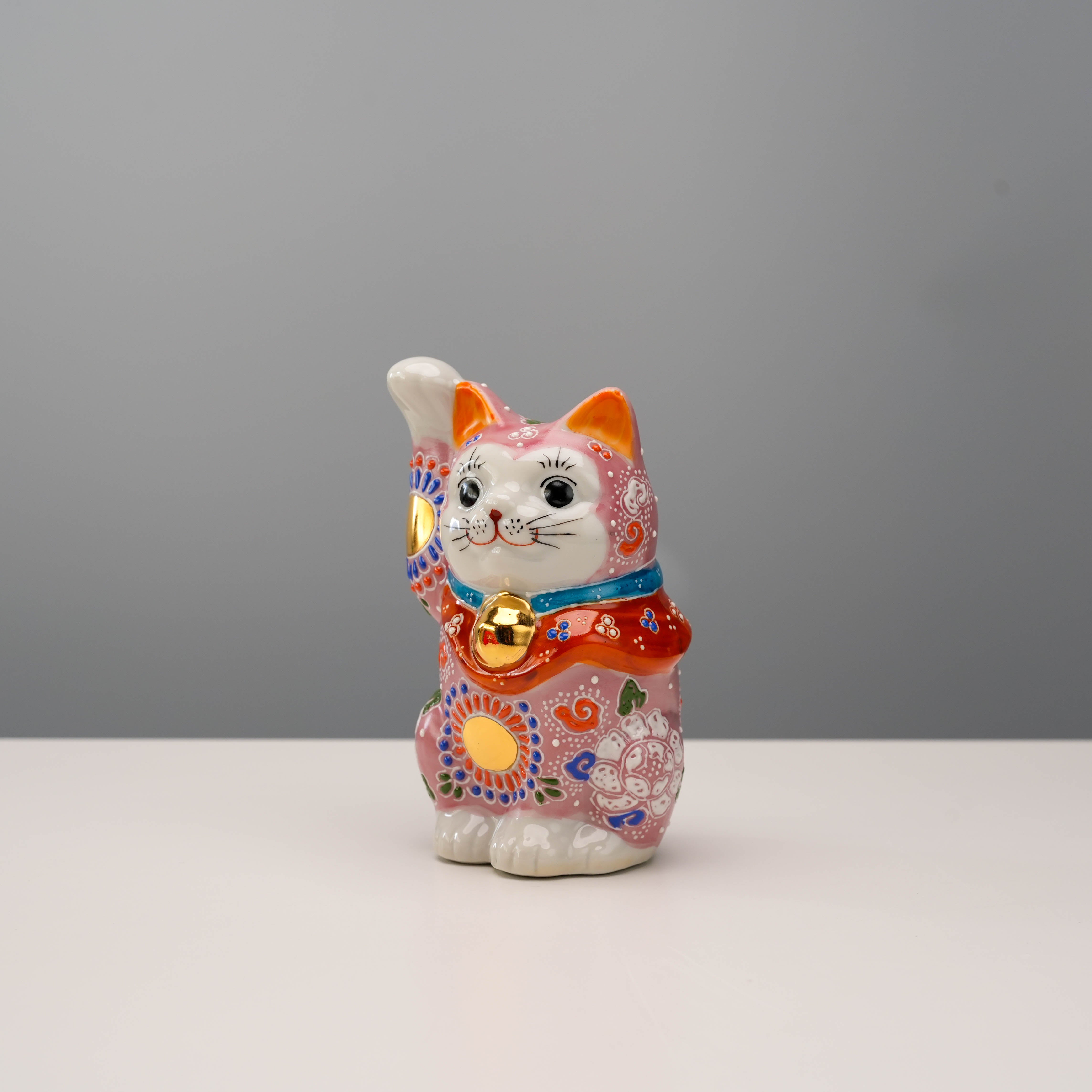 Kutani Ware Cat Ornament - Lucky Cat with pink floral patterns and raised right paw, hand-painted ceramic figurine for home decor or gifting.