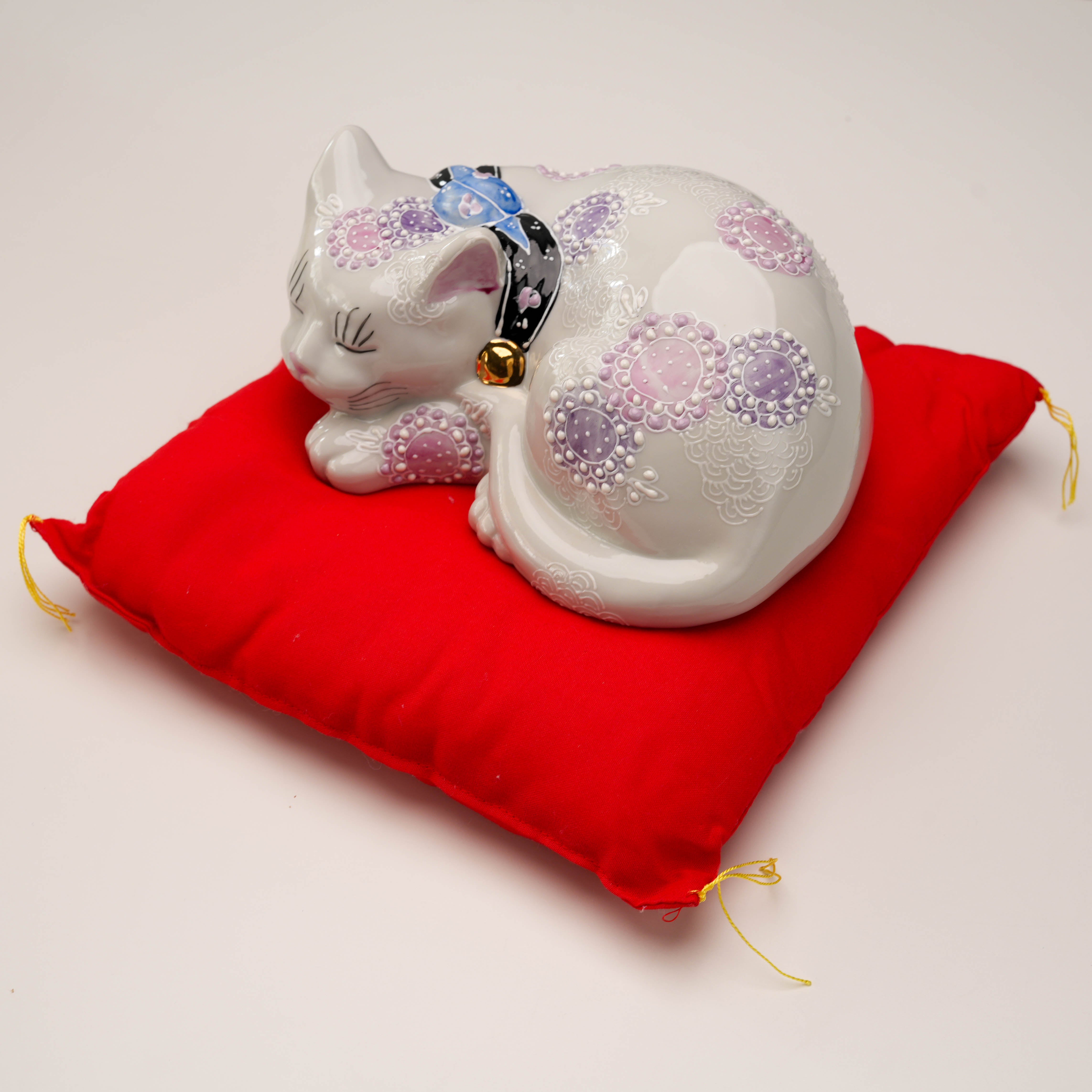Top view of Kutani Ware Sleeping Cat figurine with intricate purple floral patterns on red cushion, perfect for home and garden decor.