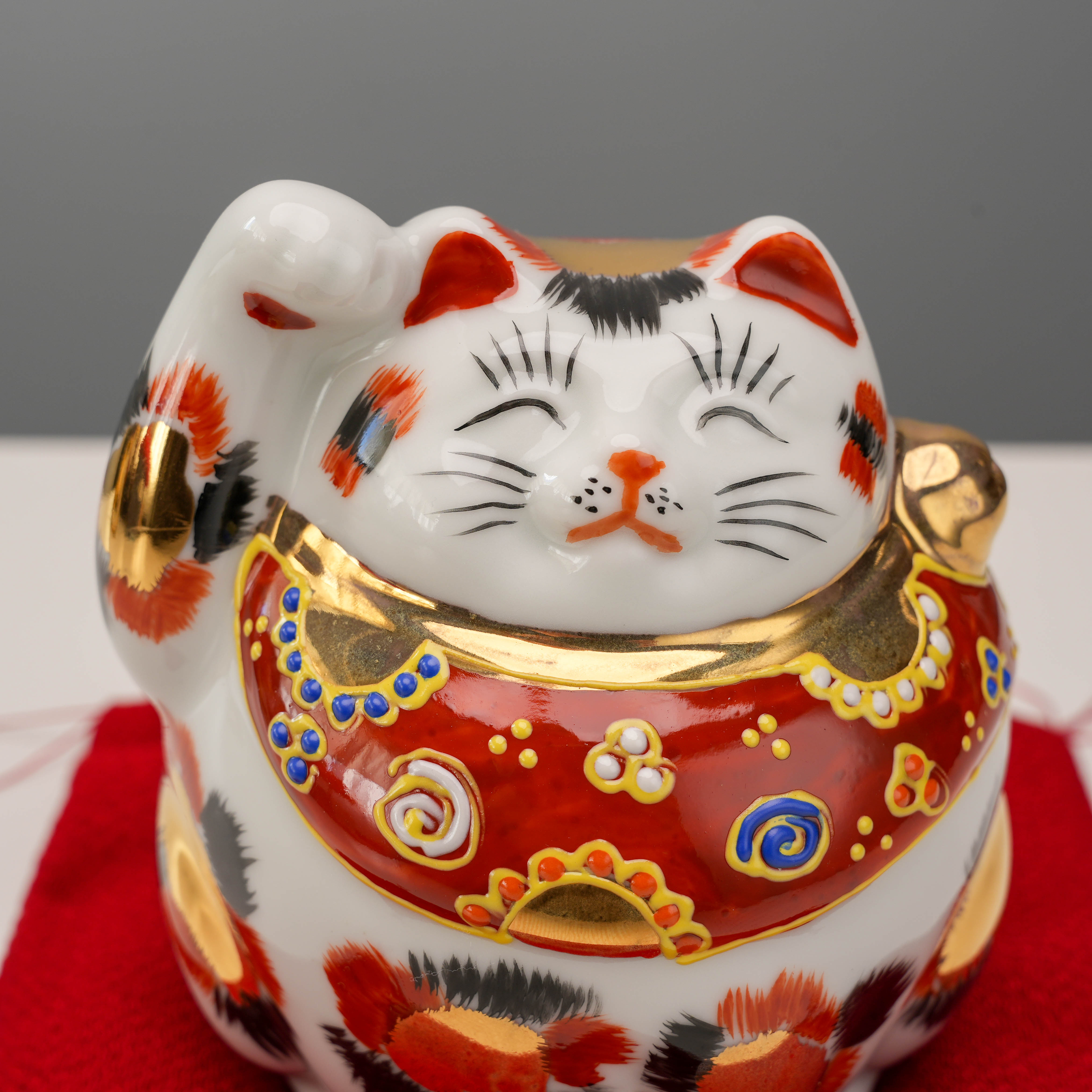 Close-up of Kutani Ware Cat – Lucky Calico showing intricate gold calico spots and red collar with floral patterns, ideal for gifting.
