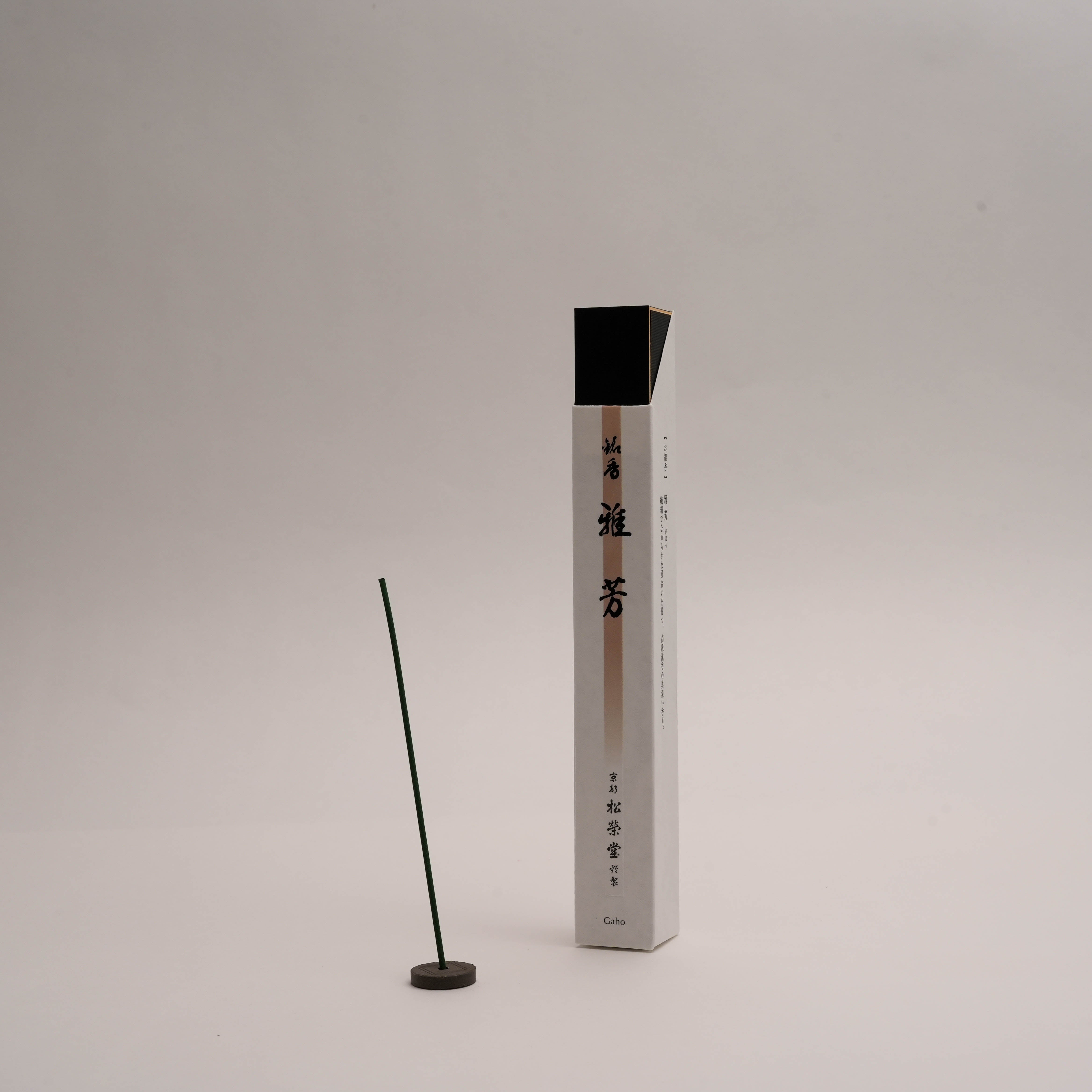 Shoyeido Premium Incense - Gaho stick burning upright in holder beside elegant white box. Features agarwood, clove, and spice blend for home fragrance.