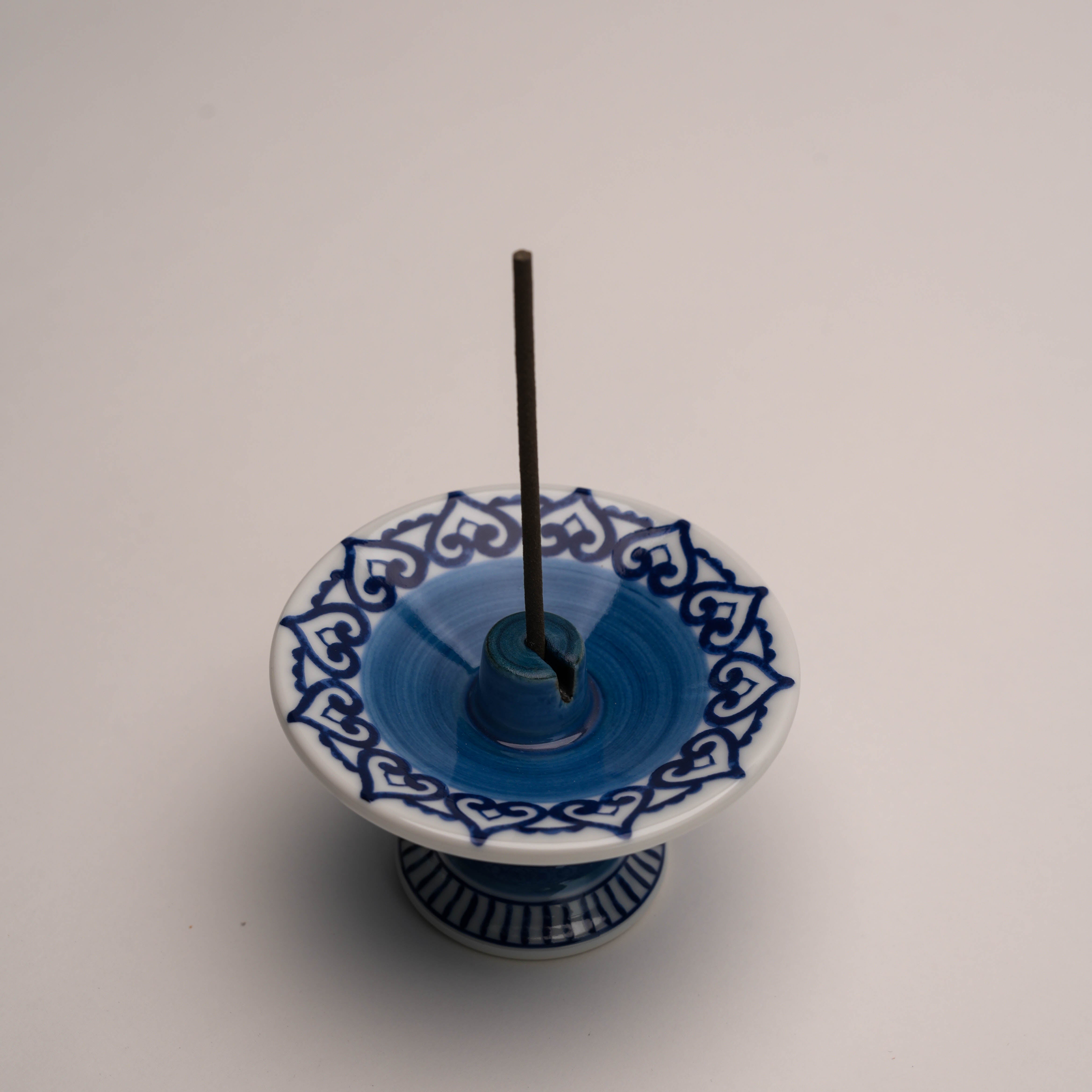 Top view of Shoyeido Arabesque Incense Burner with stick incense, showing detailed blue arabesque pattern and central holder for incense.