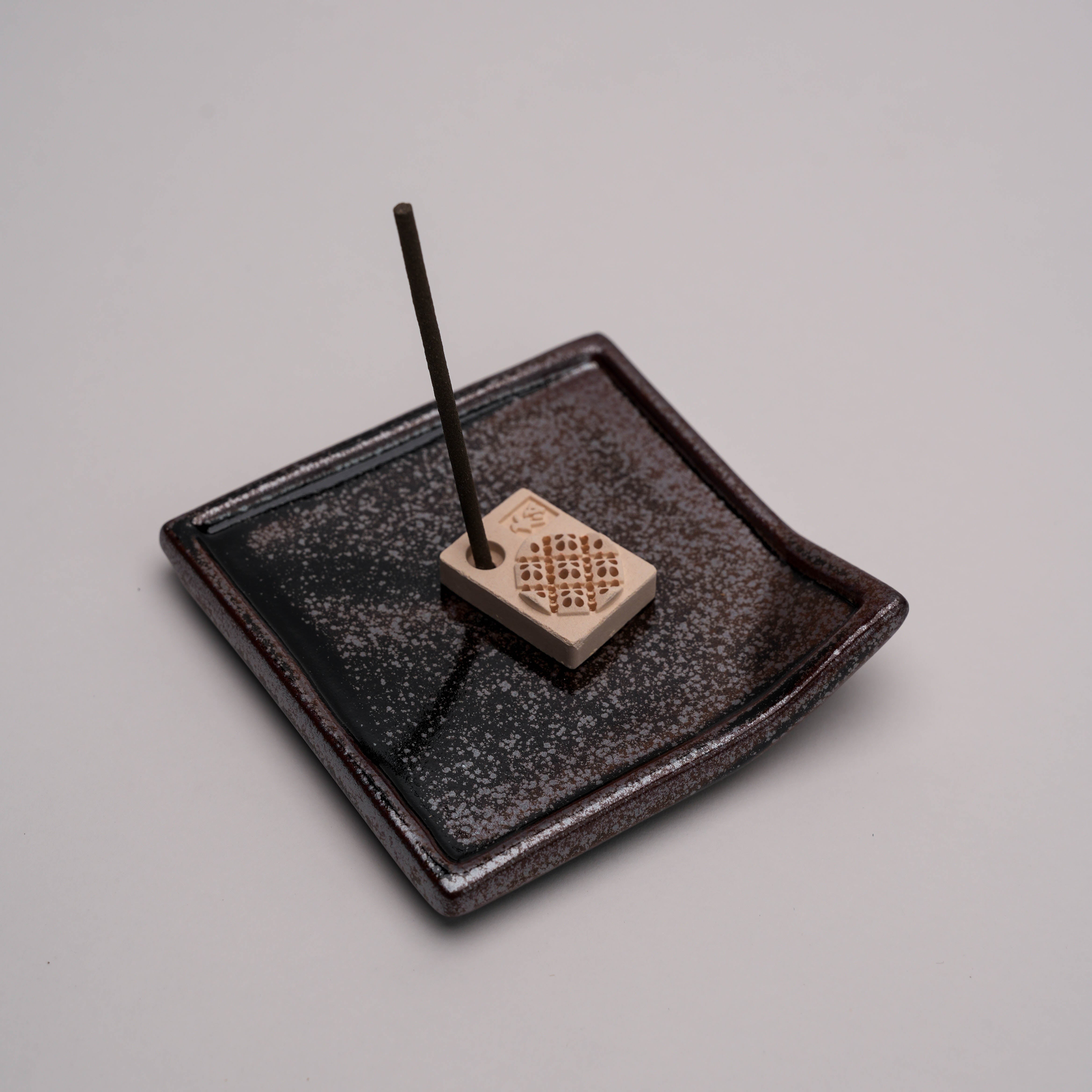 Close-up of incense holder tray with stick incense setup, part of the Shoyeido Cat Incense Burner set for clean ash containment.