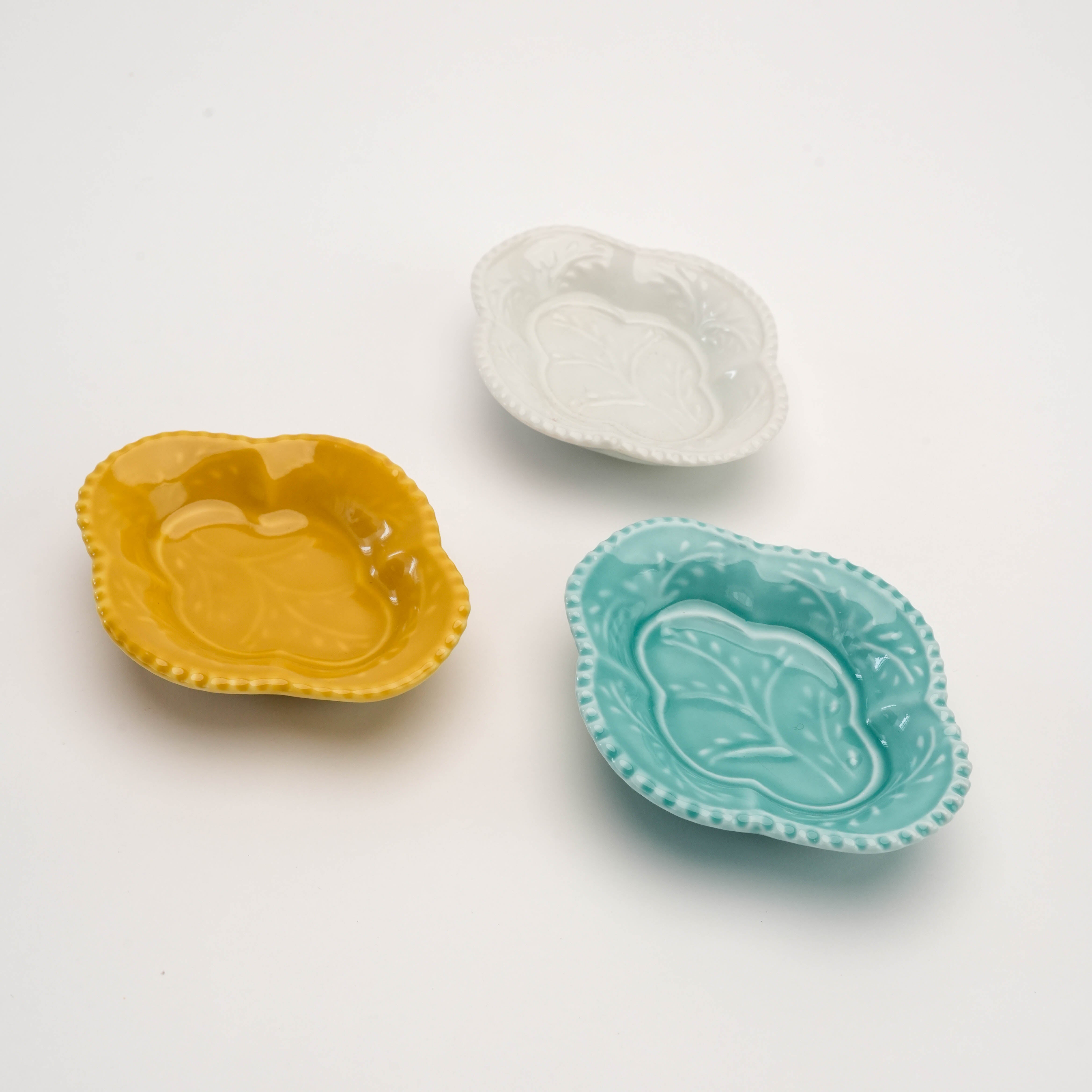Set of three Arita Ware Quince-shaped condiment dishes in white, celadon, and yellow with embossed leaf design. Elegant Japanese craftsmanship for dining decor.