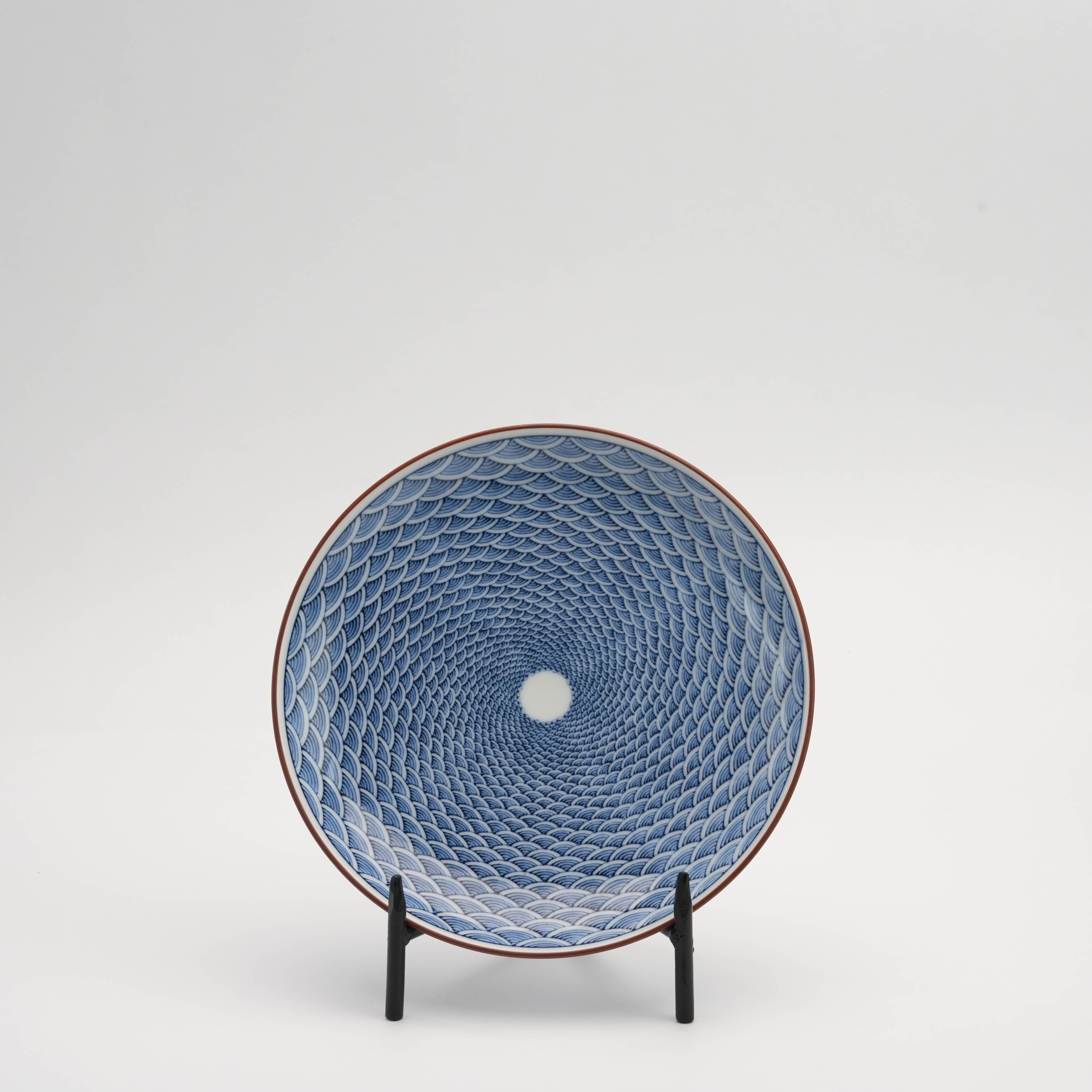 Arita Ware Seigaiha Plate - Small Wave Design displayed upright on a stand, showcasing intricate blue ocean wave patterns for serving or decor.
