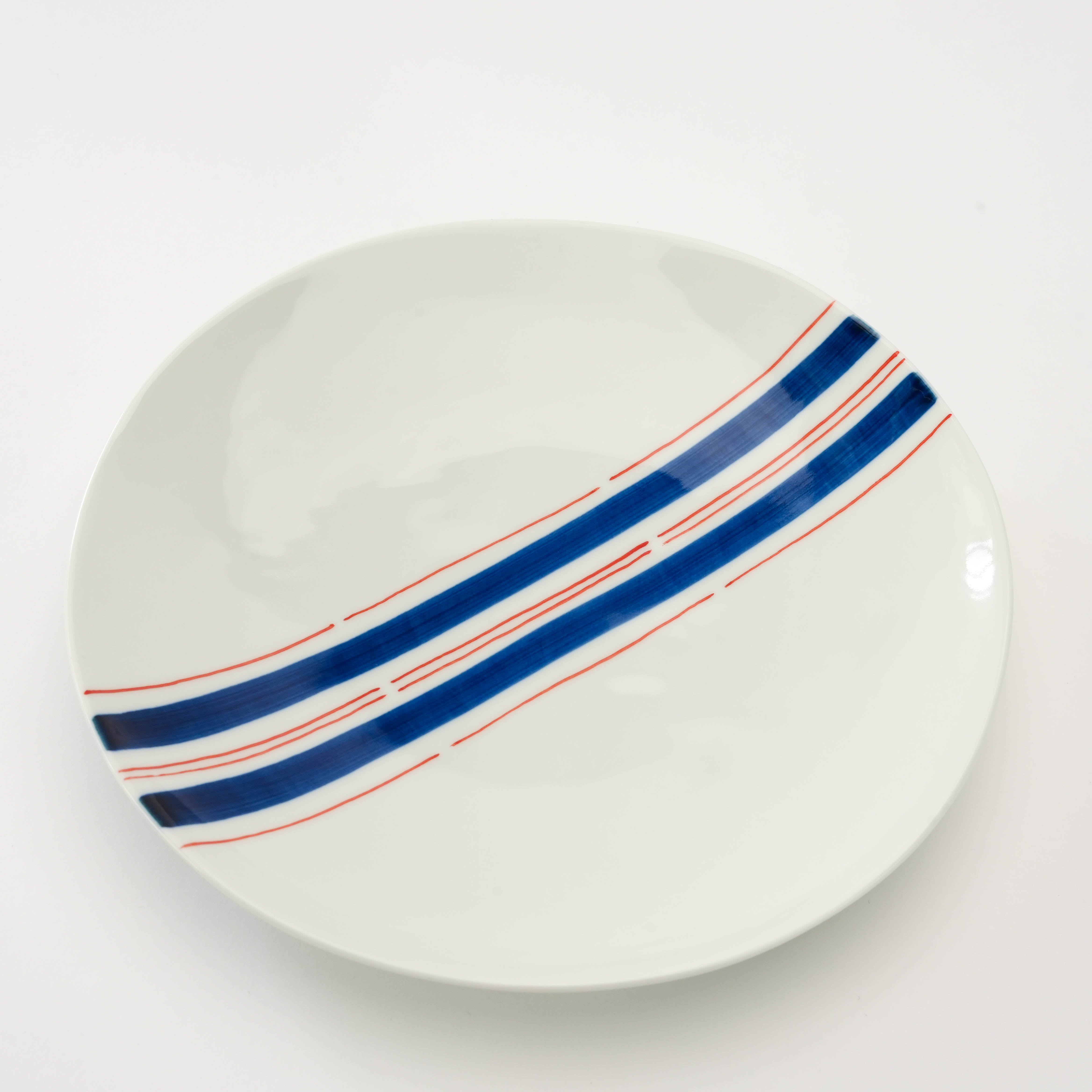Top view of Arita Ware Stripes Plate with Obi-Tokusa Design, showcasing hand-painted blue and red stripes on smooth white porcelain surface.