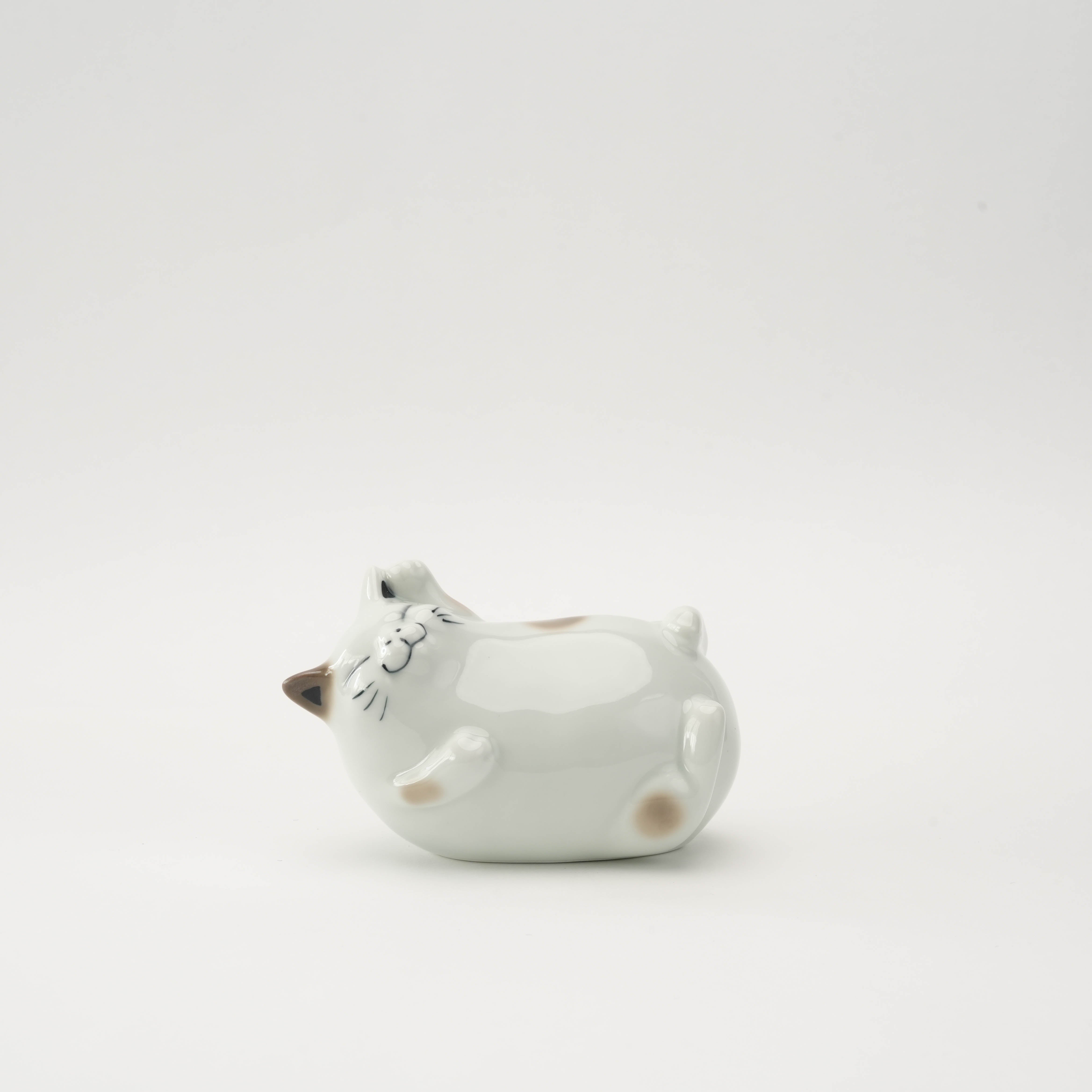 Arita Ware Cat Ornament - Laughing Cat in brown porcelain, lying on its back with a joyful expression, ideal for home decor or gifting.