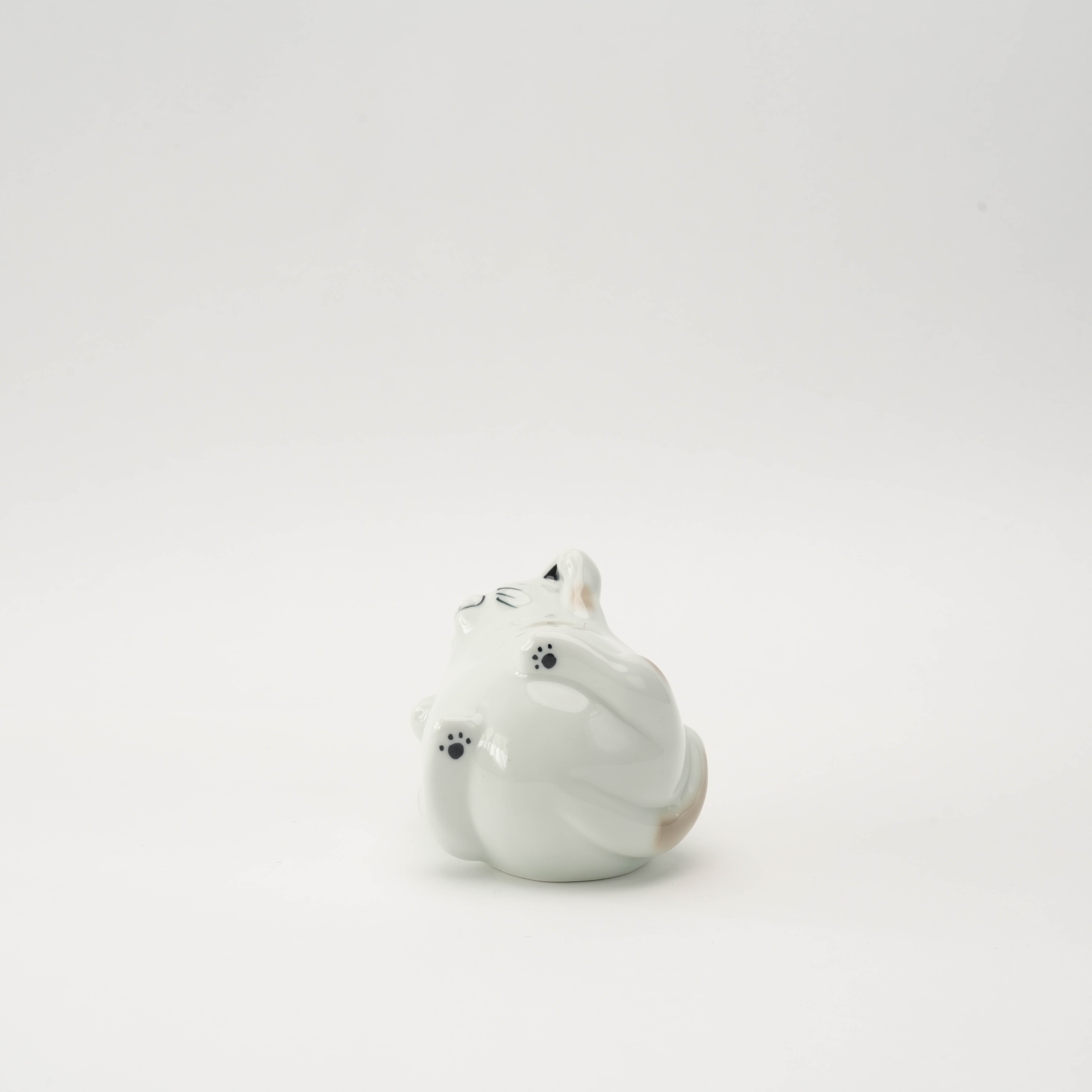 Bottom view of the porcelain Arita Ware Laughing Cat Ornament, highlighting its paw prints and rounded form for decorative charm.