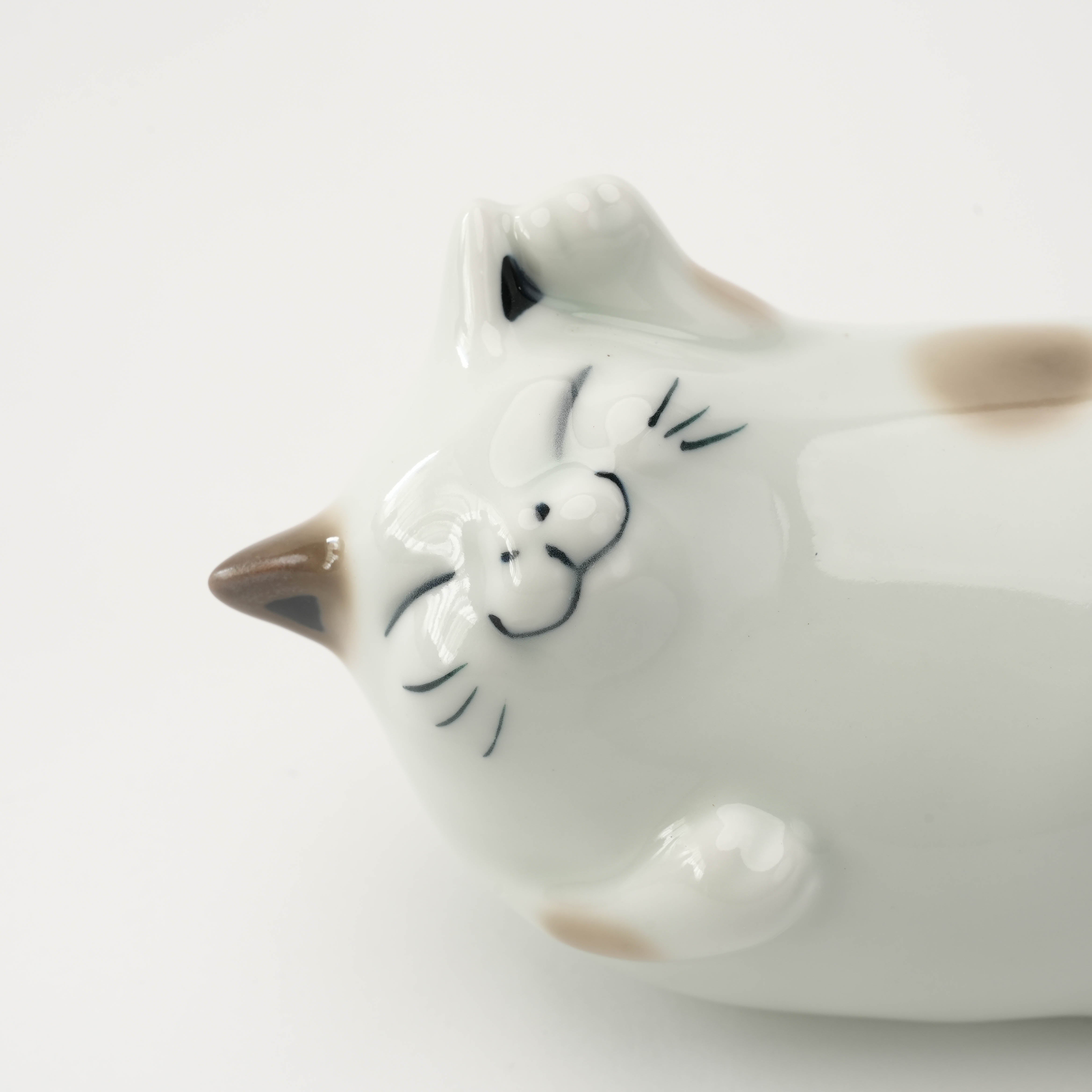 Close-up of the Arita Ware Cat Ornament's smiling face, featuring delicate hand-painted whiskers and soft brown ear accents.
