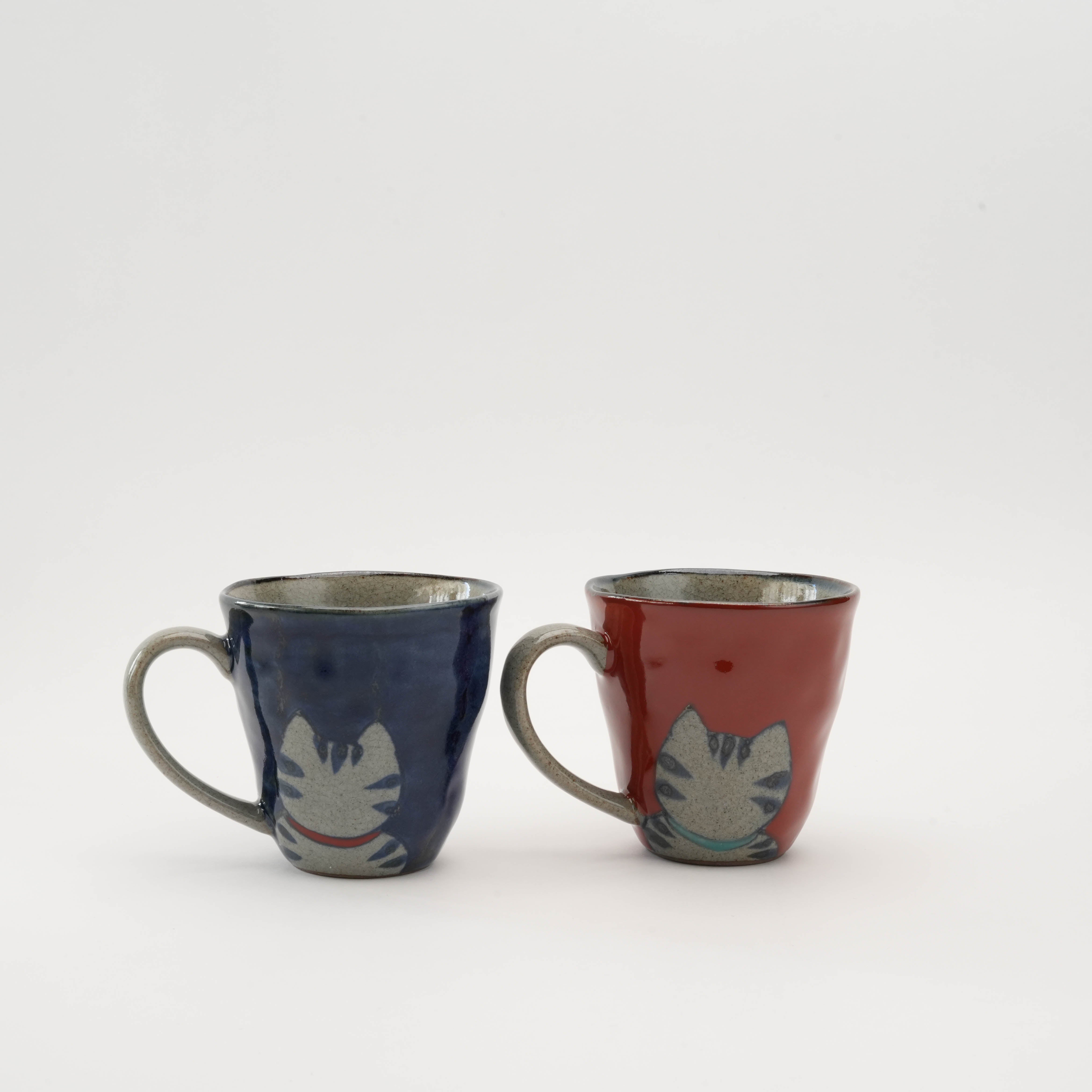 Back view of Arita Ware Lucky Cat Pair Mugs showing cat tail design, crafted in blue and red ceramic for whimsical tableware charm.