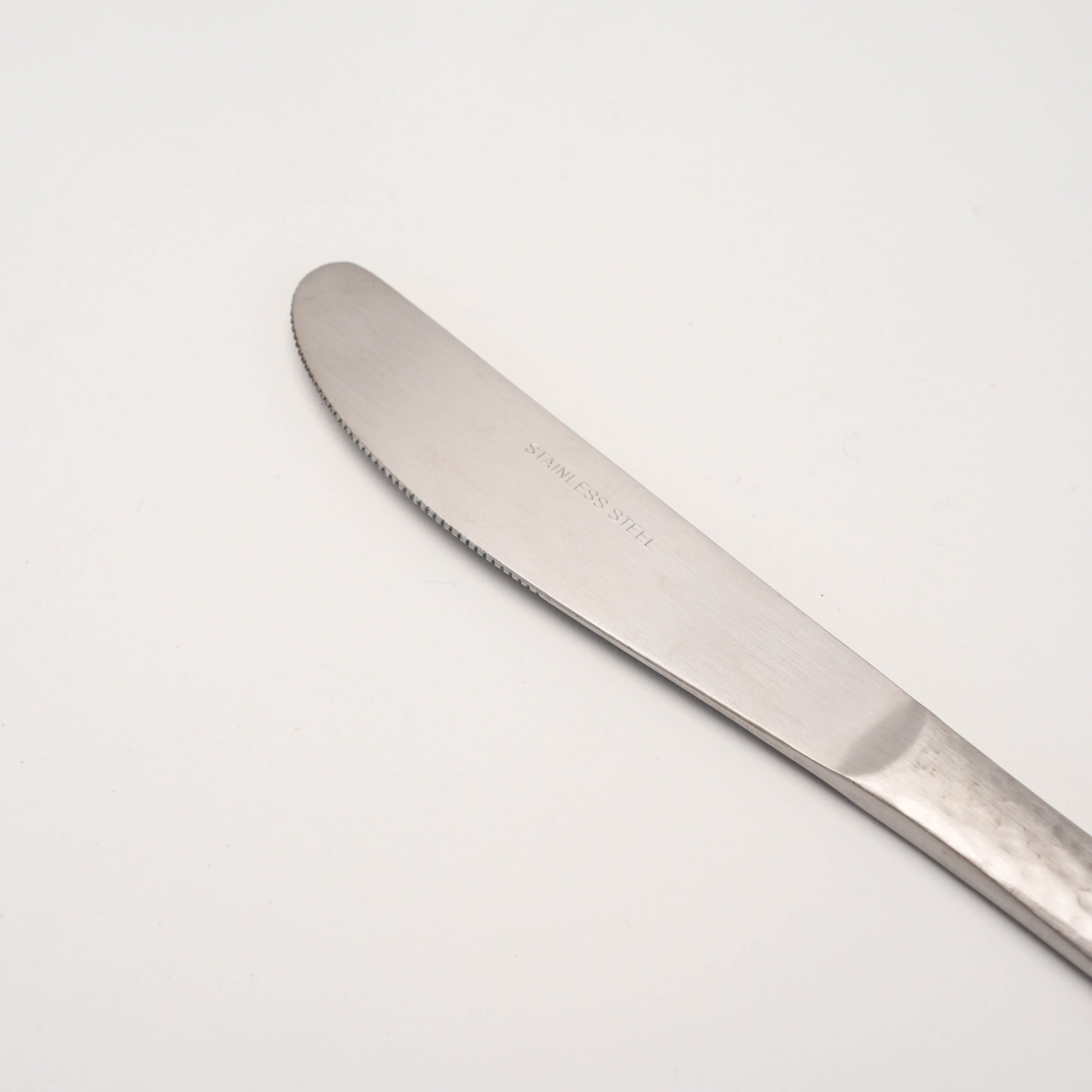Close-up of Tsubamesanjo Nagomi Wafu Knife-Hammered blade with 'Stainless Steel' engraving, highlighting fine serration and polished finish.