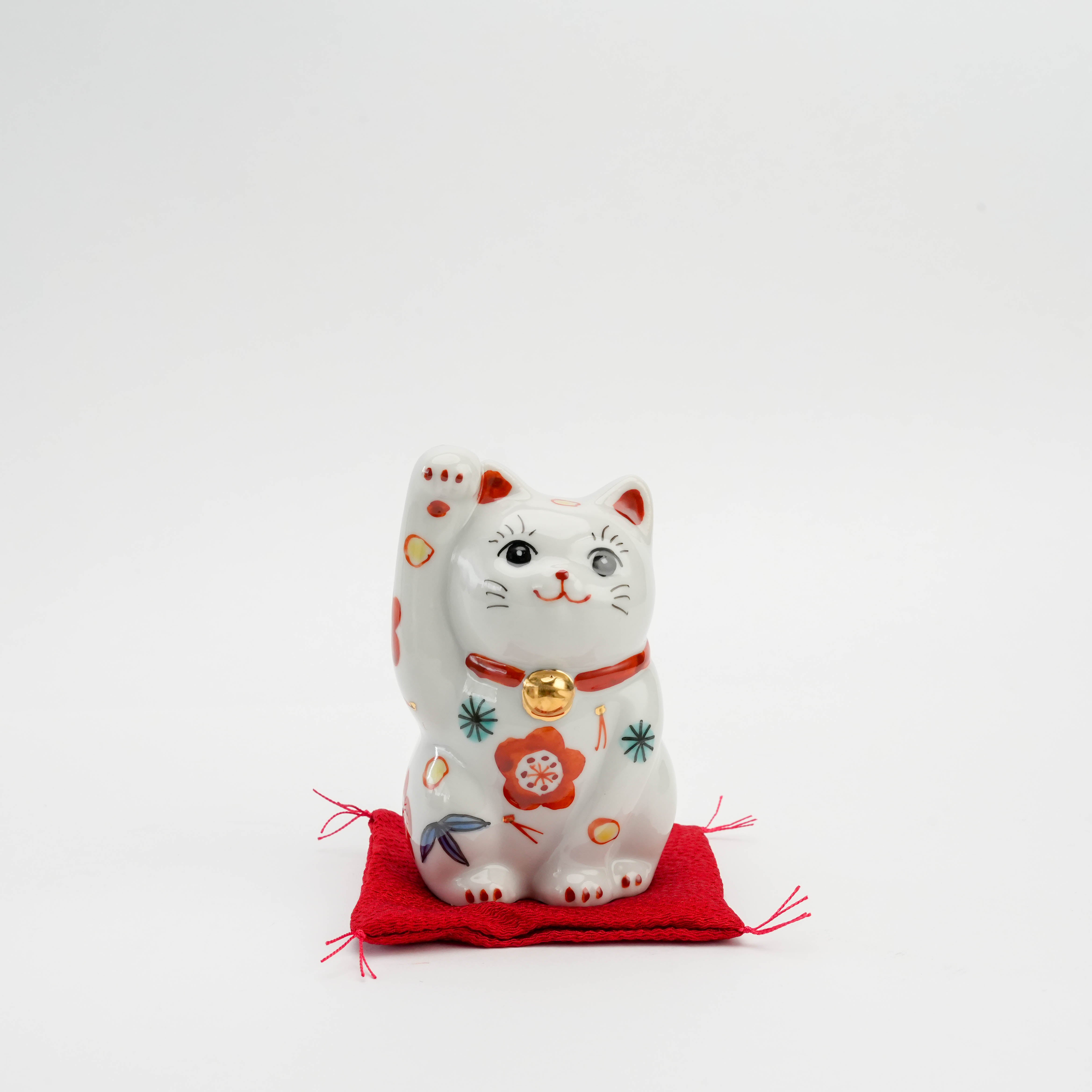 Kutani Ware Pine Cat Ornament with Sho Chiku Bai motifs, hand-painted porcelain figurine on red cushion, symbolizing fortune and prosperity.