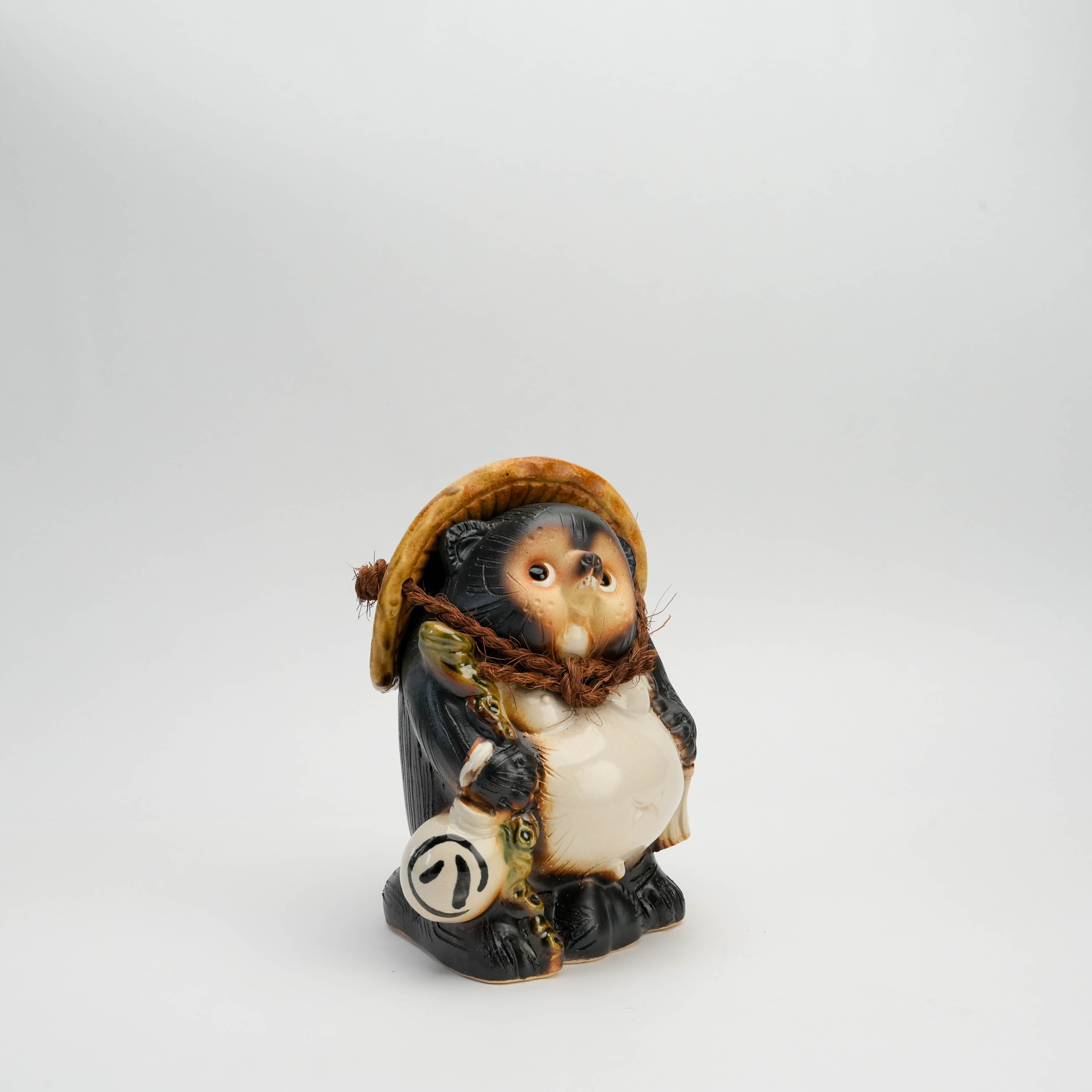 Shigaraki Ware 'Hineri' Male Lucky Tanuki Raccoon Dog Ornament angled view showing detailed ceramic craftsmanship and traditional lucky charm elements.
