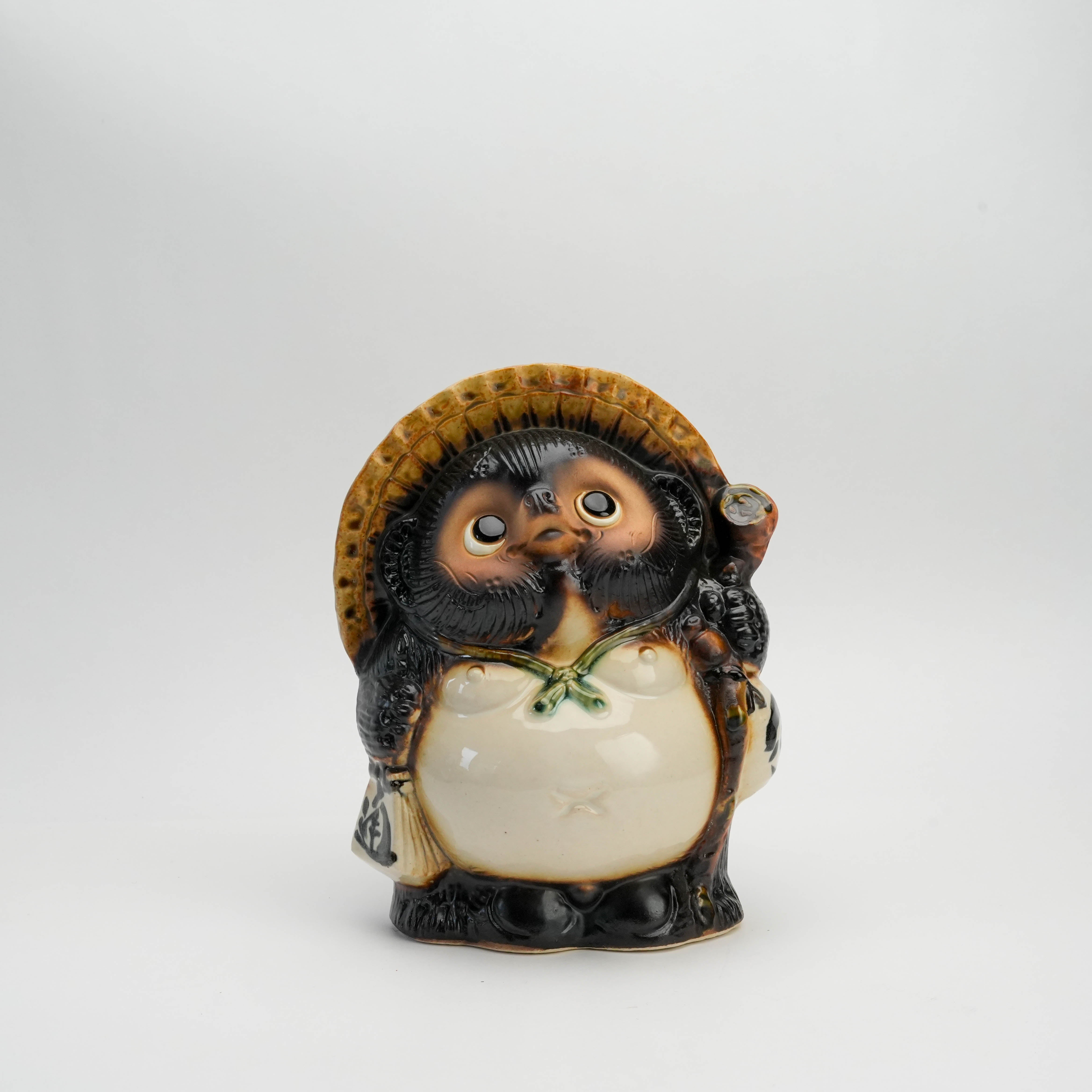 Front view of Lucky Tanuki Raccoon Ornament - Fukufuku, a Shigaraki Ware ceramic symbol of prosperity with straw hat and sake bottle.