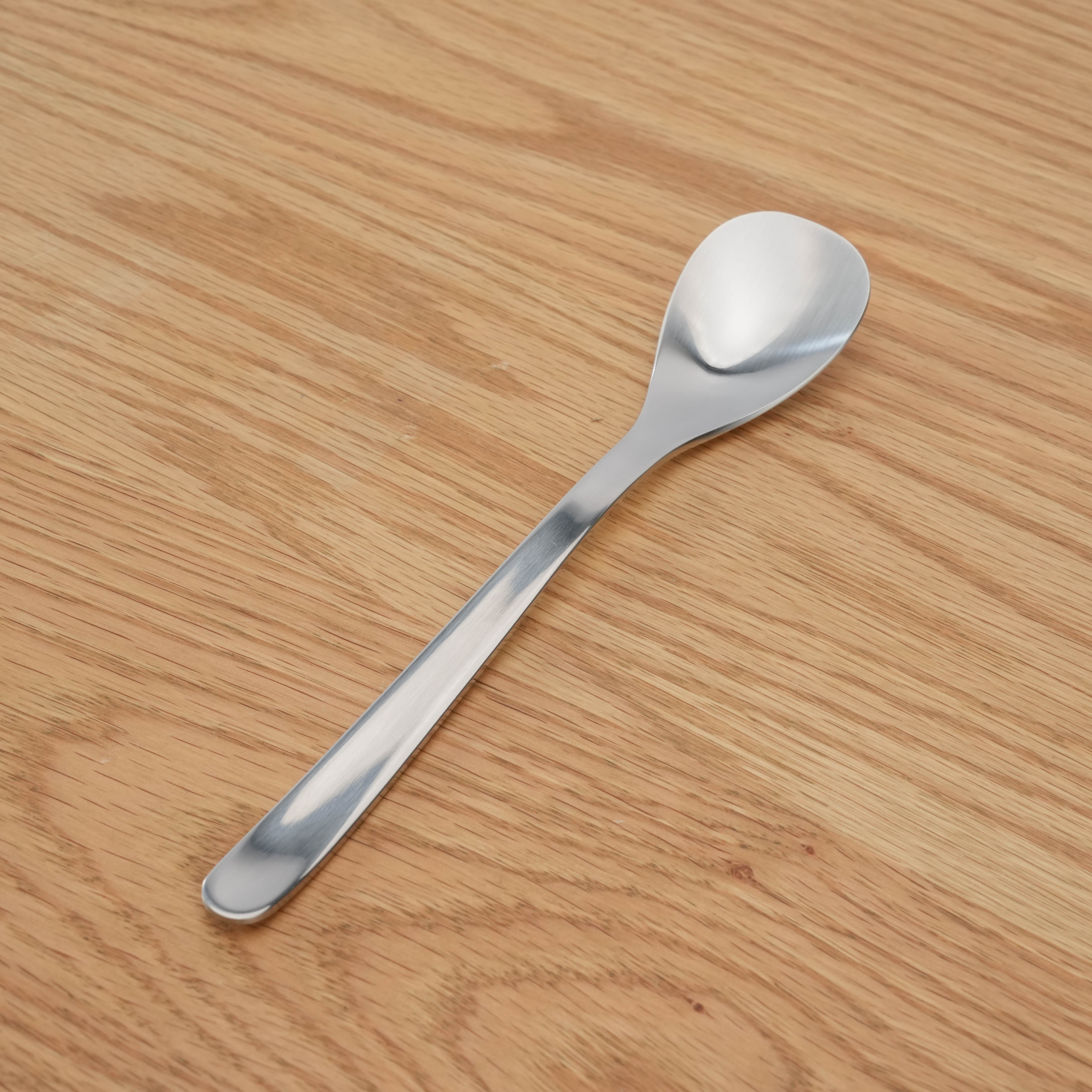 Stainless Steel Curry Spoon - Sori Yanagi with seamless design, shown on wooden surface. Ideal for elegant and practical dining use.