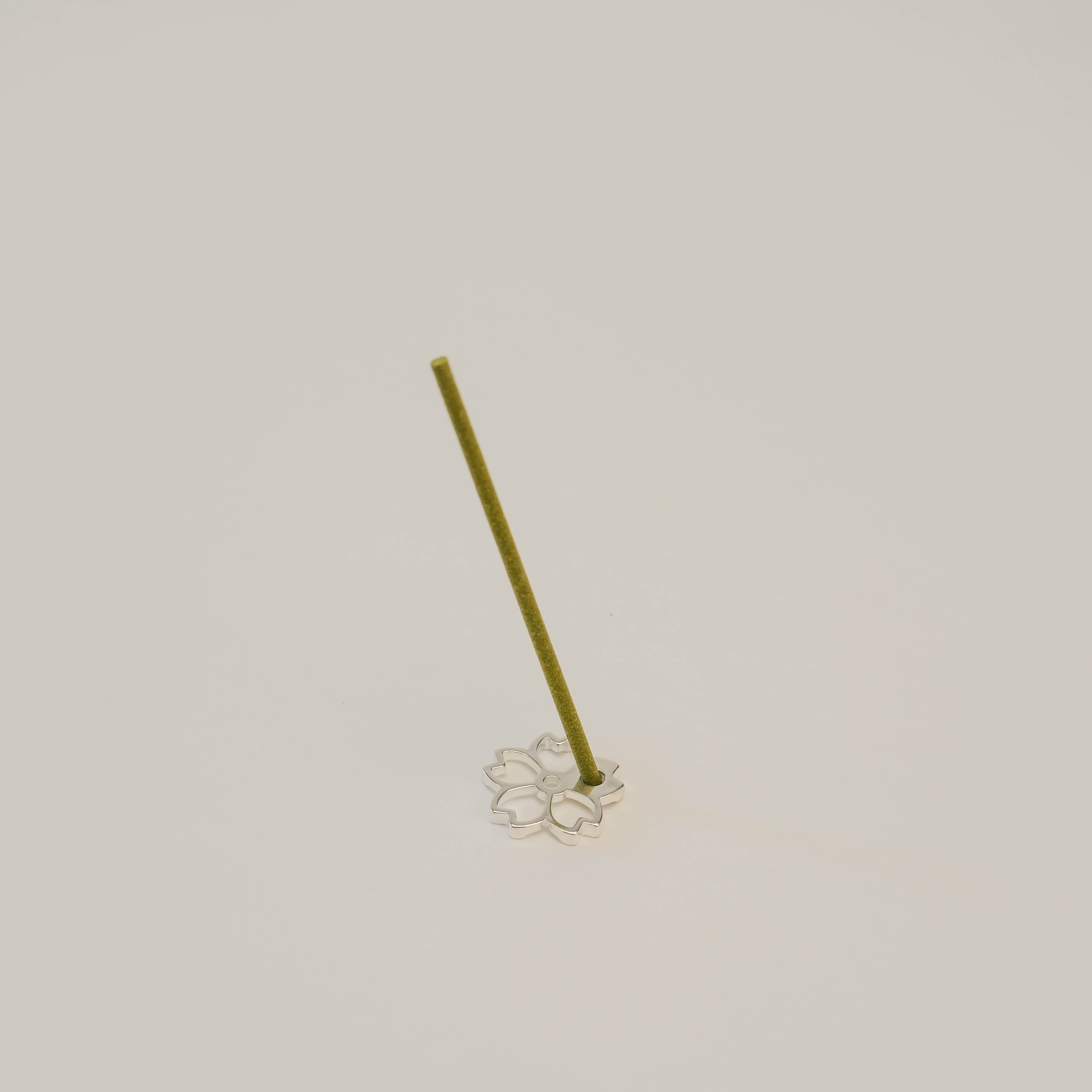 Sterling silver Shoyeido Cherry Blossoms incense holder with incense stick inserted. Elegant and compact for refined aromatherapy setups.
