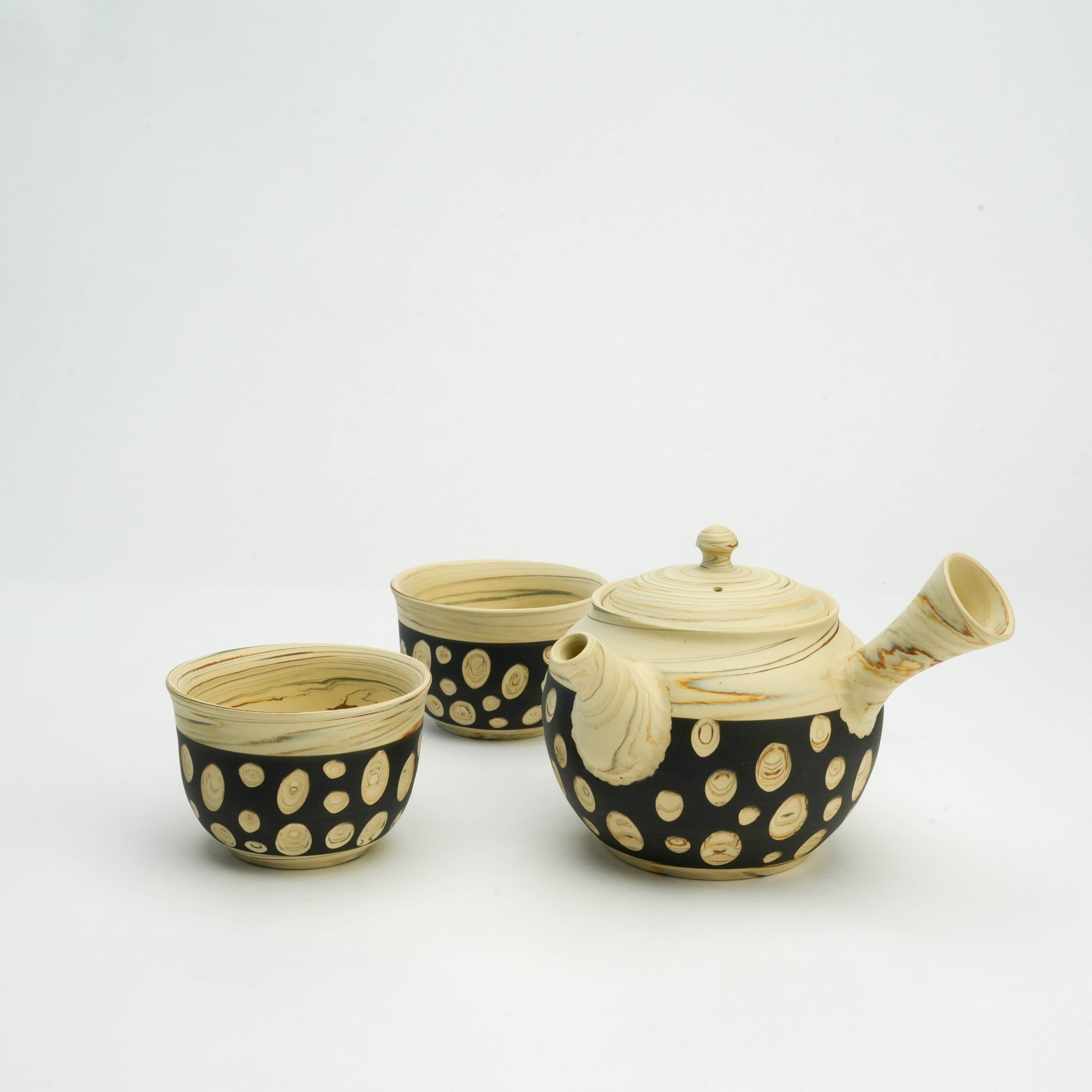 Tokoname Polka Dot Tea Set by Kenji Touen featuring a teapot and two cups with nerikomi patterns in black and beige. Japanese ceramic artistry.