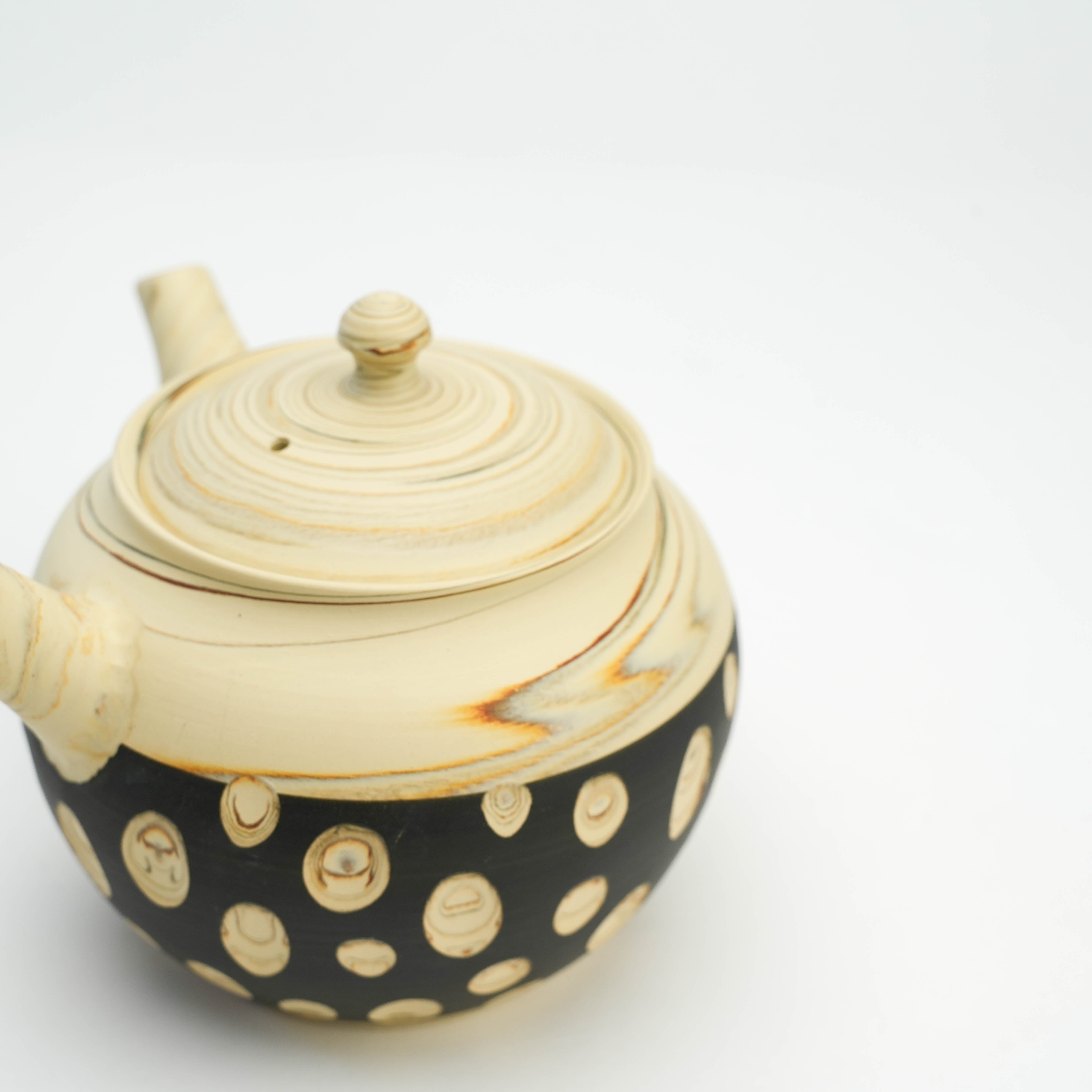 Detail of Tokoname Teapot lid and body showcasing swirling beige clay and black base with carved polka dot nerikomi patterns.