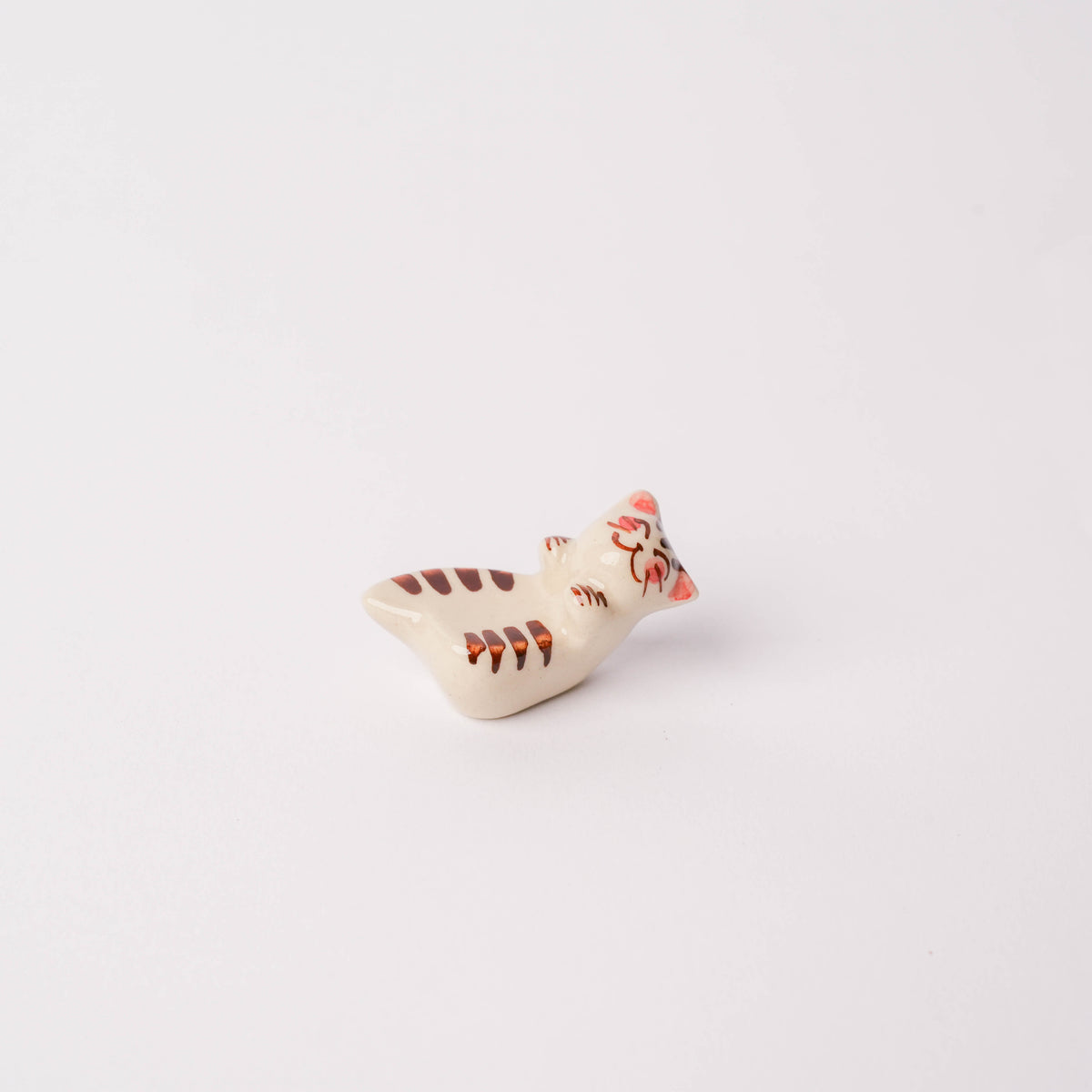 Side view of the colorful ceramic cat chopstick rest showing detailed painted stripes and facial expression