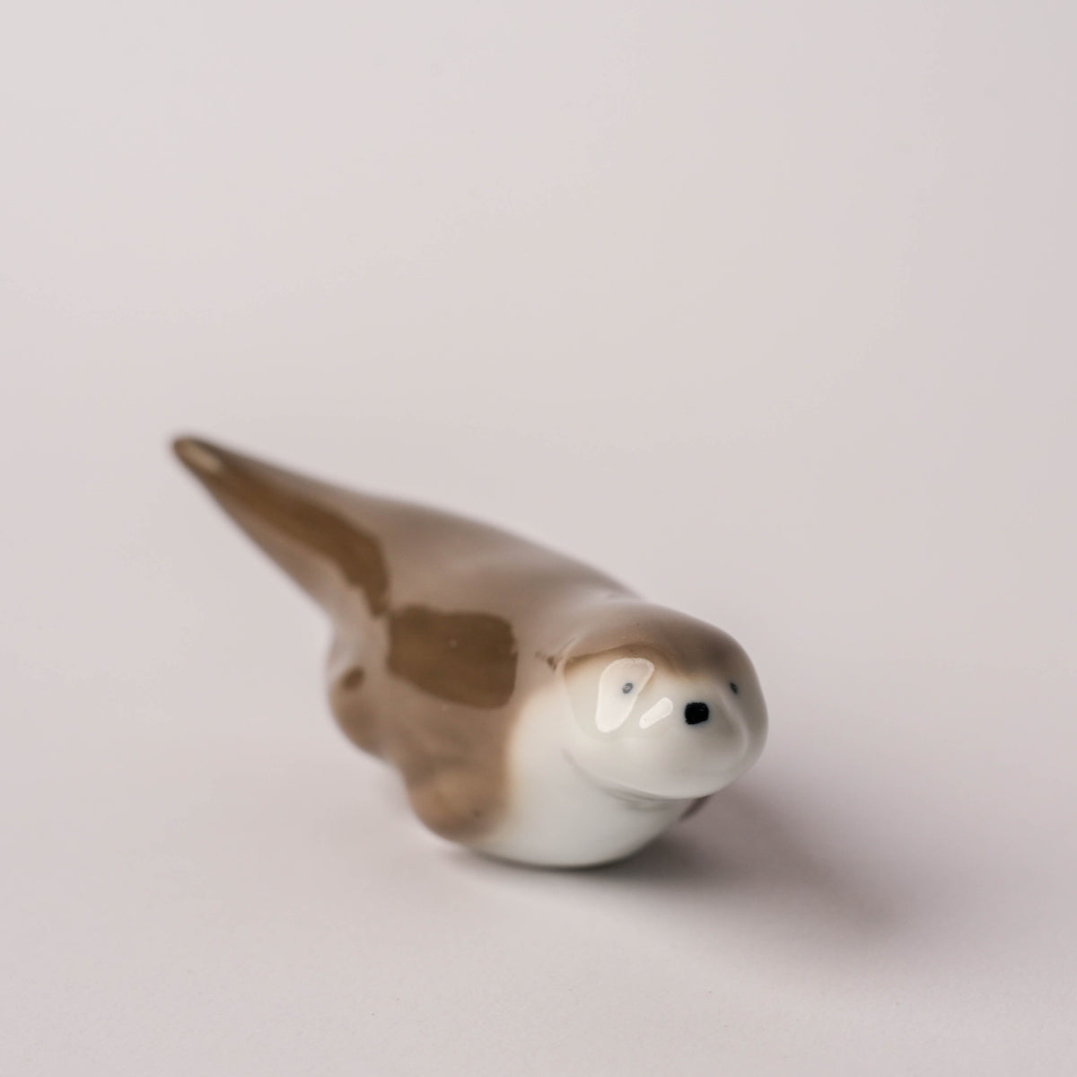 Close-up of the ceramic otter chopstick rest showing its smooth, glazed surface and delicate painted details from Japan.