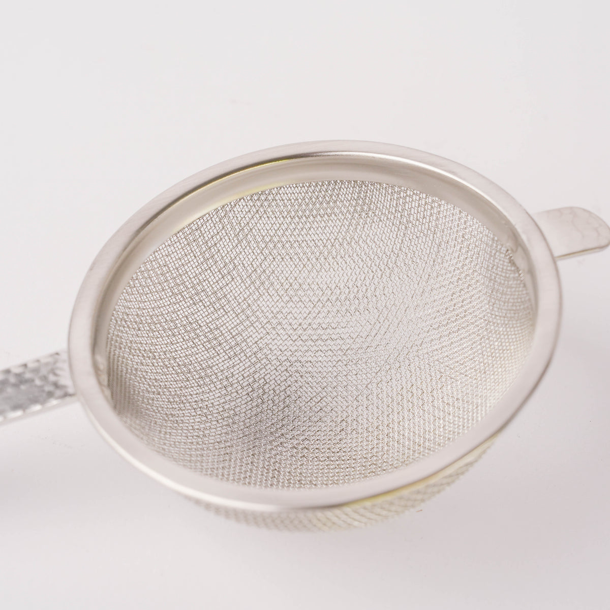 Close-up of stainless steel hammered tea strainer showing detailed fine mesh and polished rim, perfect for easy tea straining and elegant presentation