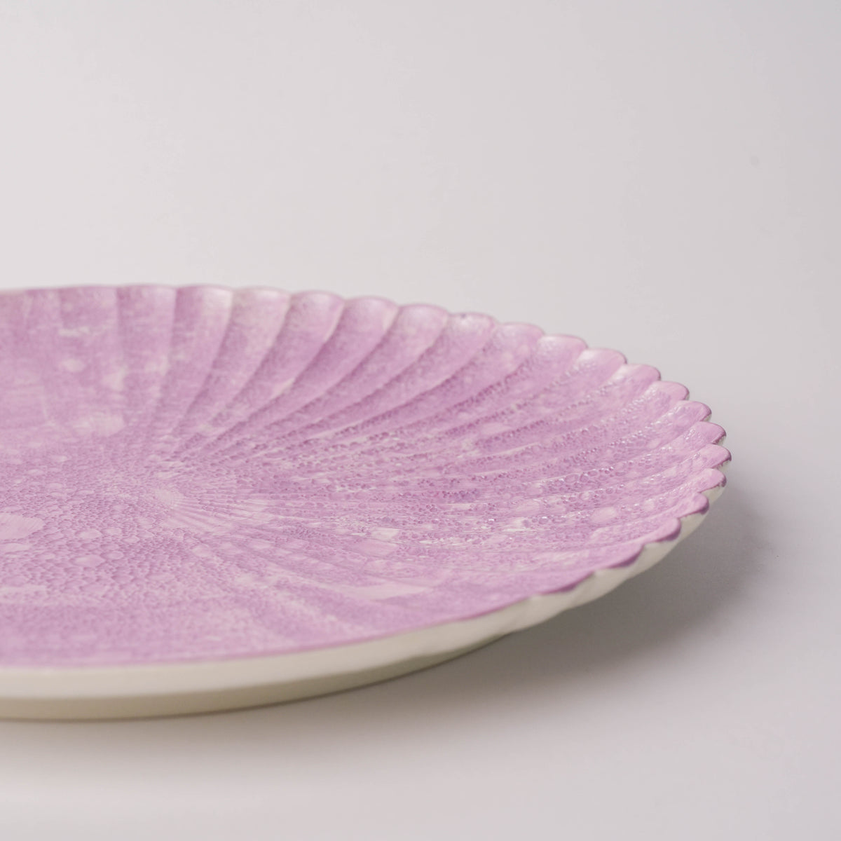 Close-up of pink bubble glass plate with scalloped rim, showing textured surface and delicate design